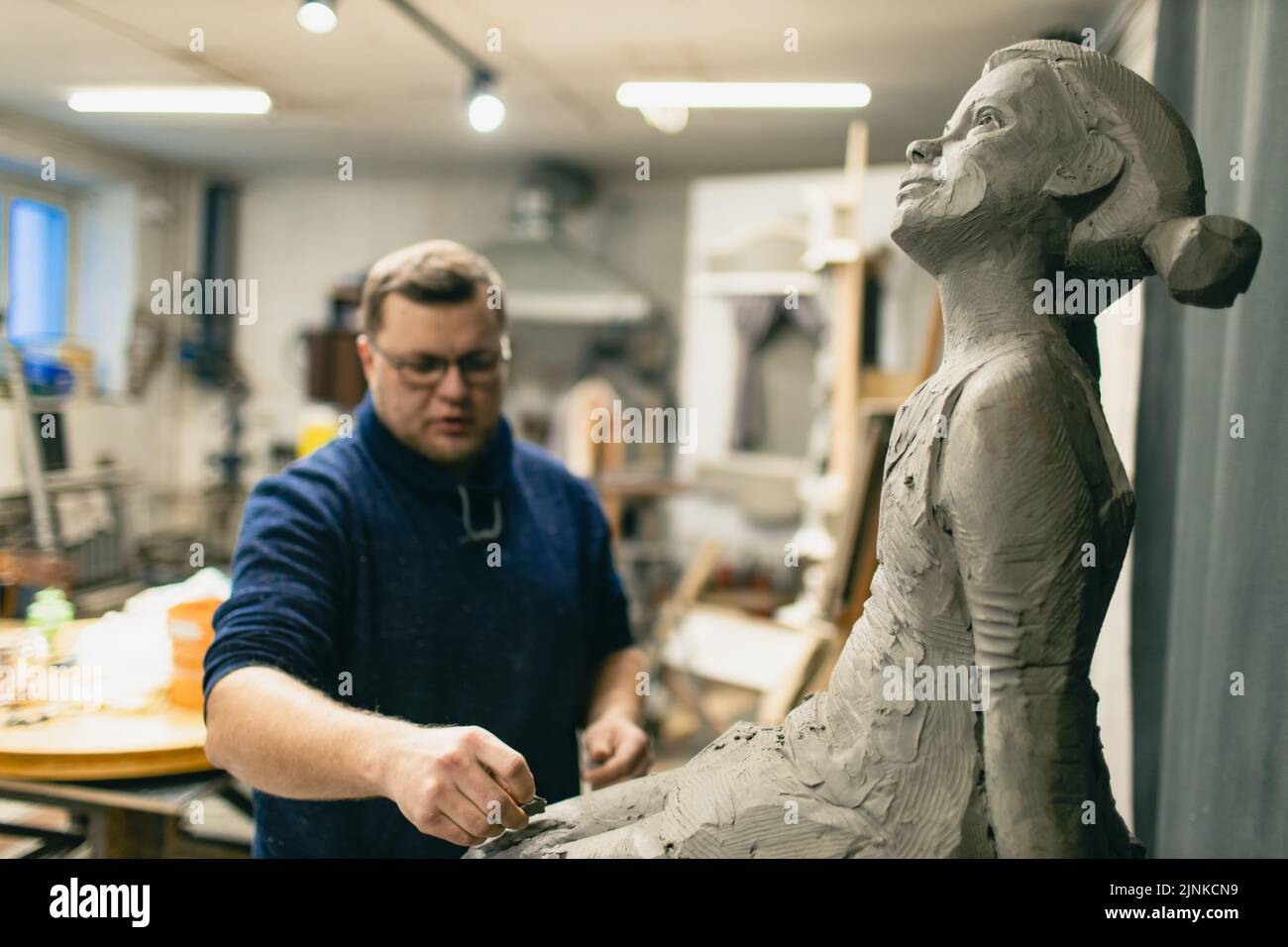 Uomo scultore crea scultura donna uomo in argilla sculpta. Laboratorio di creazione di statue artigianali. Foto Stock