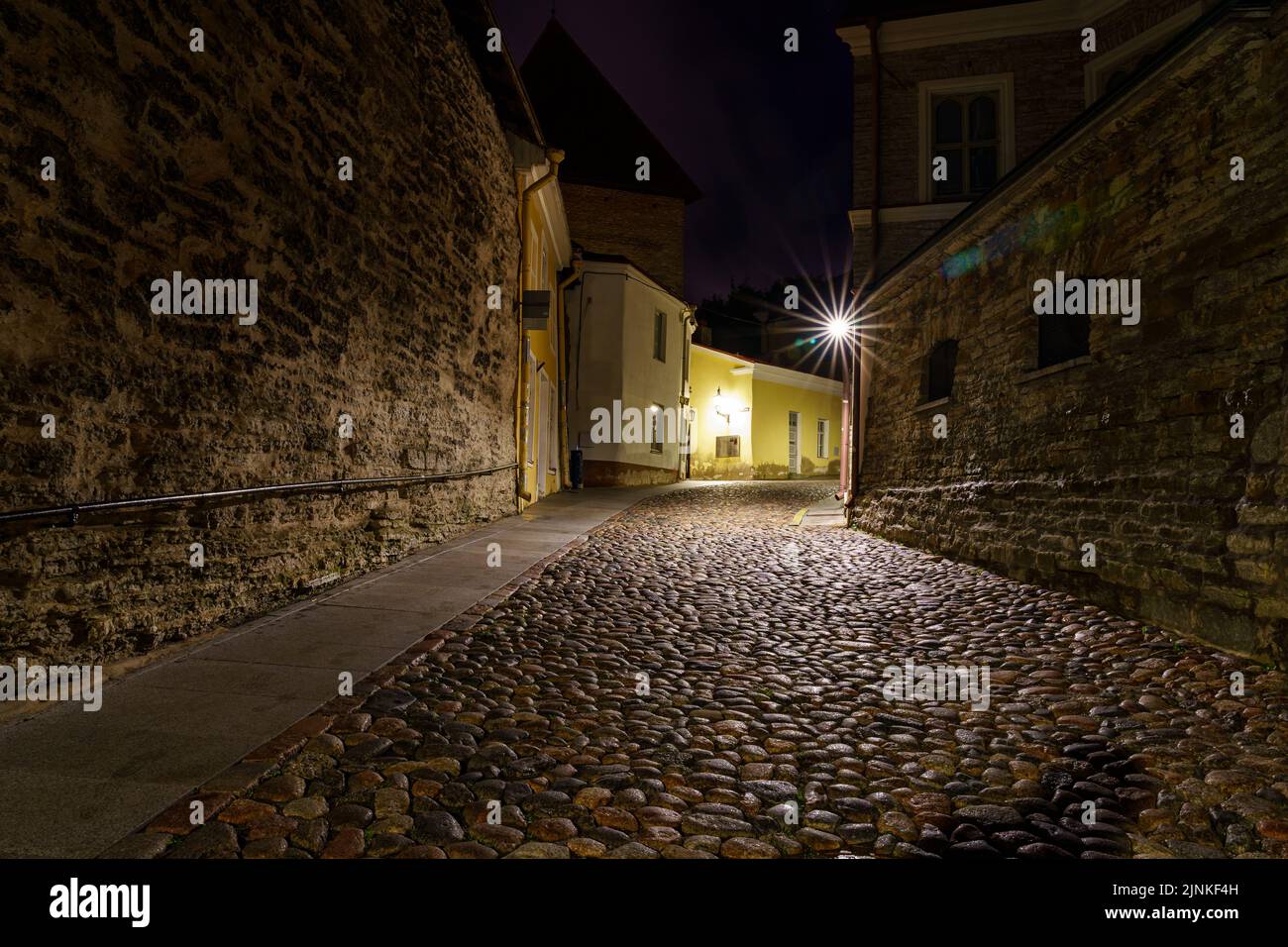 Strada acciottolata nella città di Tallinn di notte con lampioni illuminati. Foto Stock