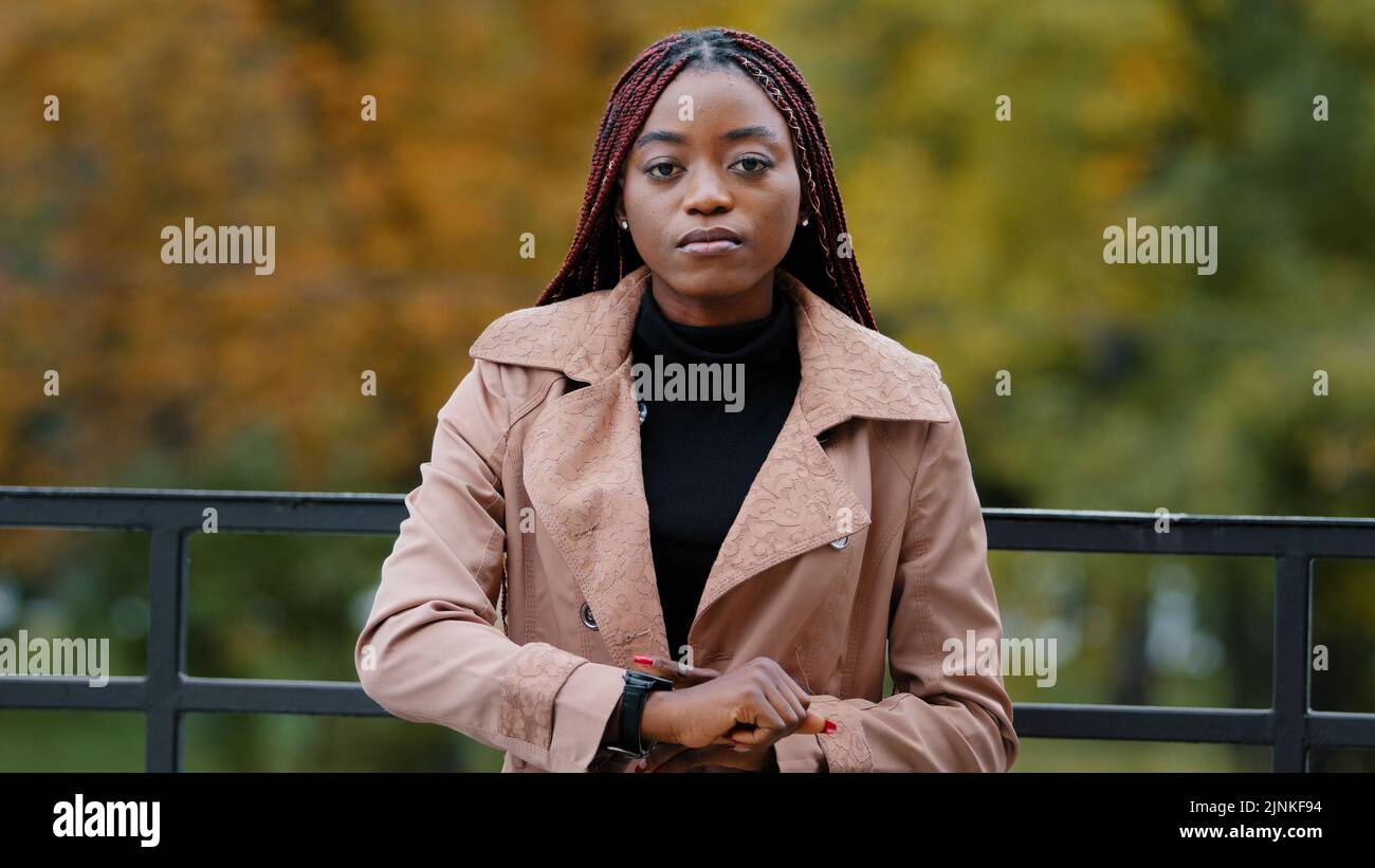 Turbato frustrato donna afroamericana mostra in guardia, contando minuti, fretta. Ritratto di bella ragazza afro in piedi nel parco autunnale da solo Foto Stock