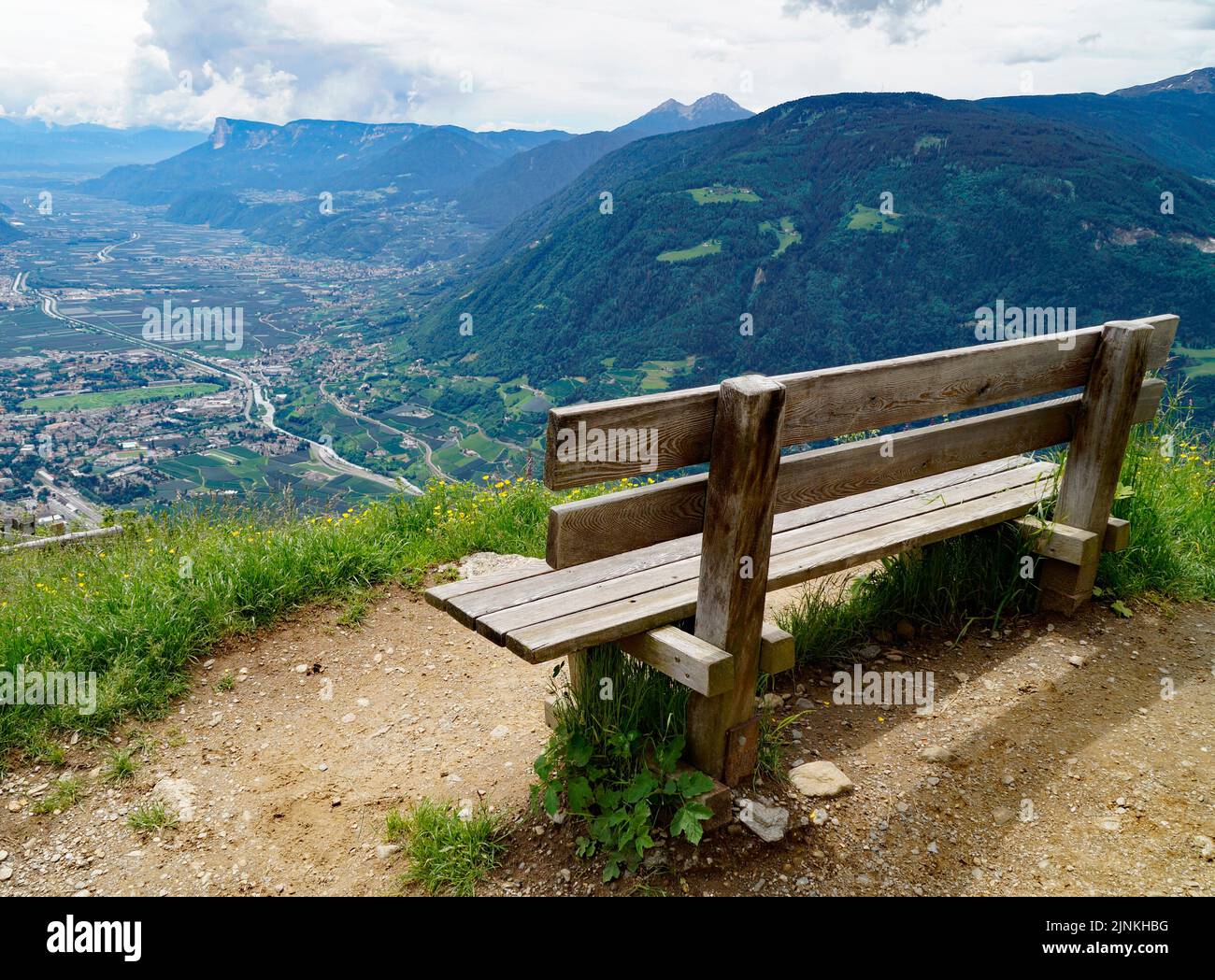 Una panchina che domina la valle alpina della città di Merano circondata dai monti del gruppo Texel (Oetztaler Alpen a Südtirol, Alto Adige, Italia) Foto Stock