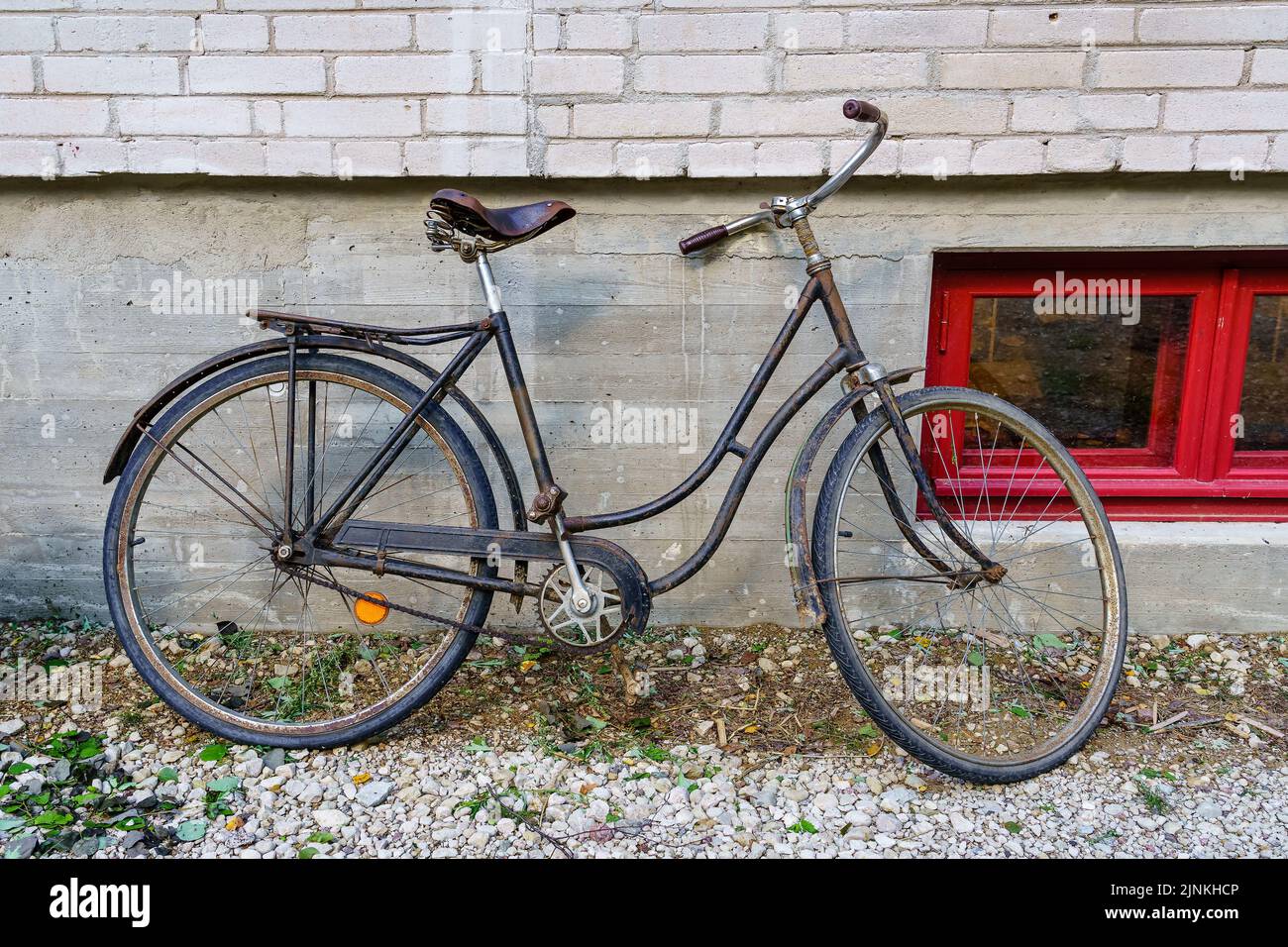 Vecchia bicicletta arrugginita parcheggiata sulle pareti di un vecchio edificio. Foto Stock