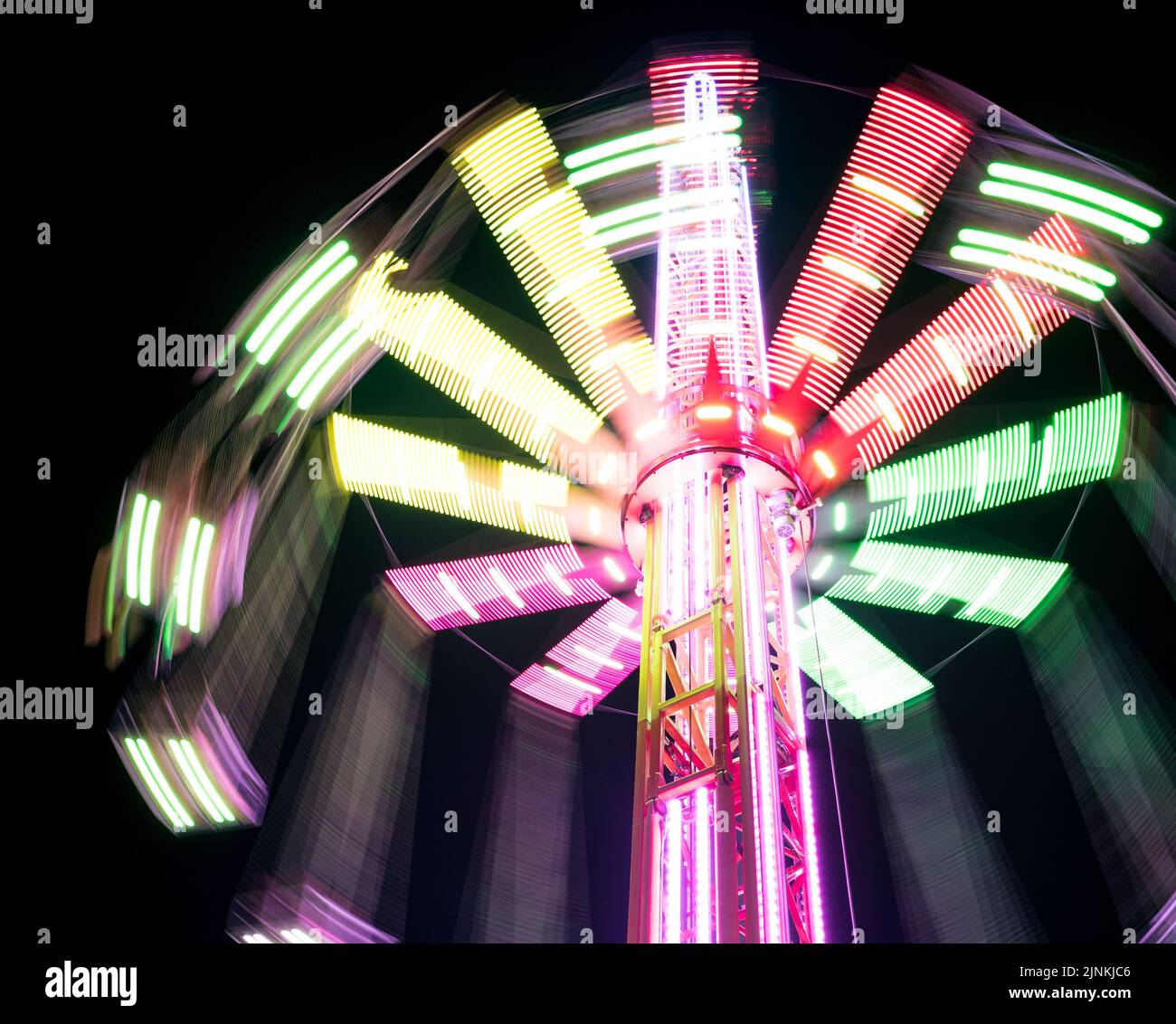 Carosello alto Star Flyer multicolore che ruota su lunghe catene in un parco divertimenti. Concetto di intrattenimento e attività ricreative. Foto Stock