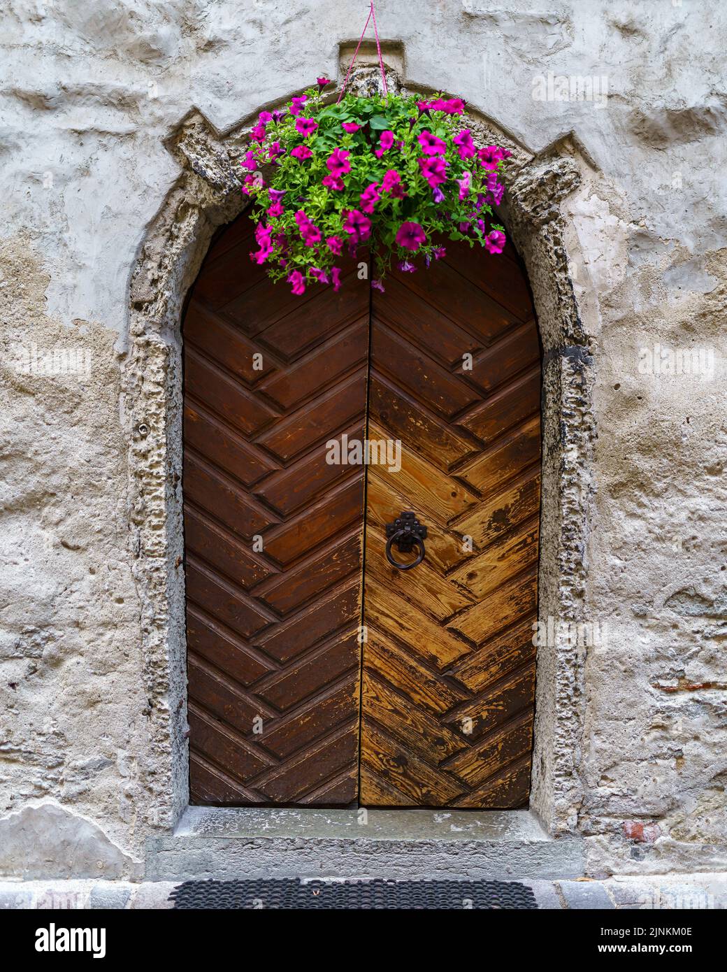 Vecchia porta in legno in edificio medievale con vaso di fiori. Foto Stock