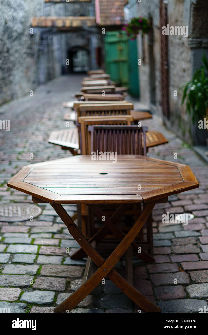 Tavoli e sedie in legno in vicolo acciottolato con un aspetto vintage. Foto Stock