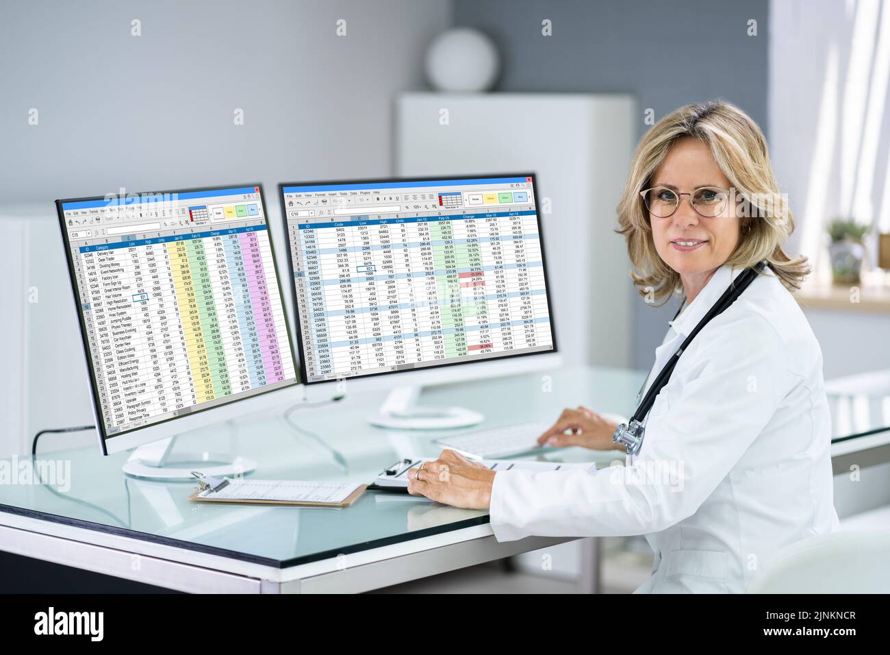 Hospital Doctor che utilizza il foglio di calcolo per i codici di fatturazione sul desktop Foto Stock