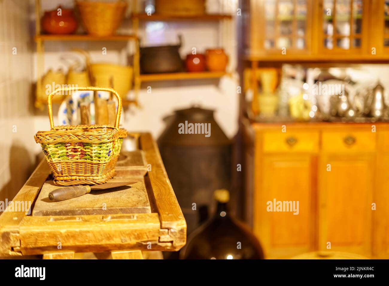 Cestino di vimini e utensili molto vecchi in cucina in legno e look vintage. Foto Stock