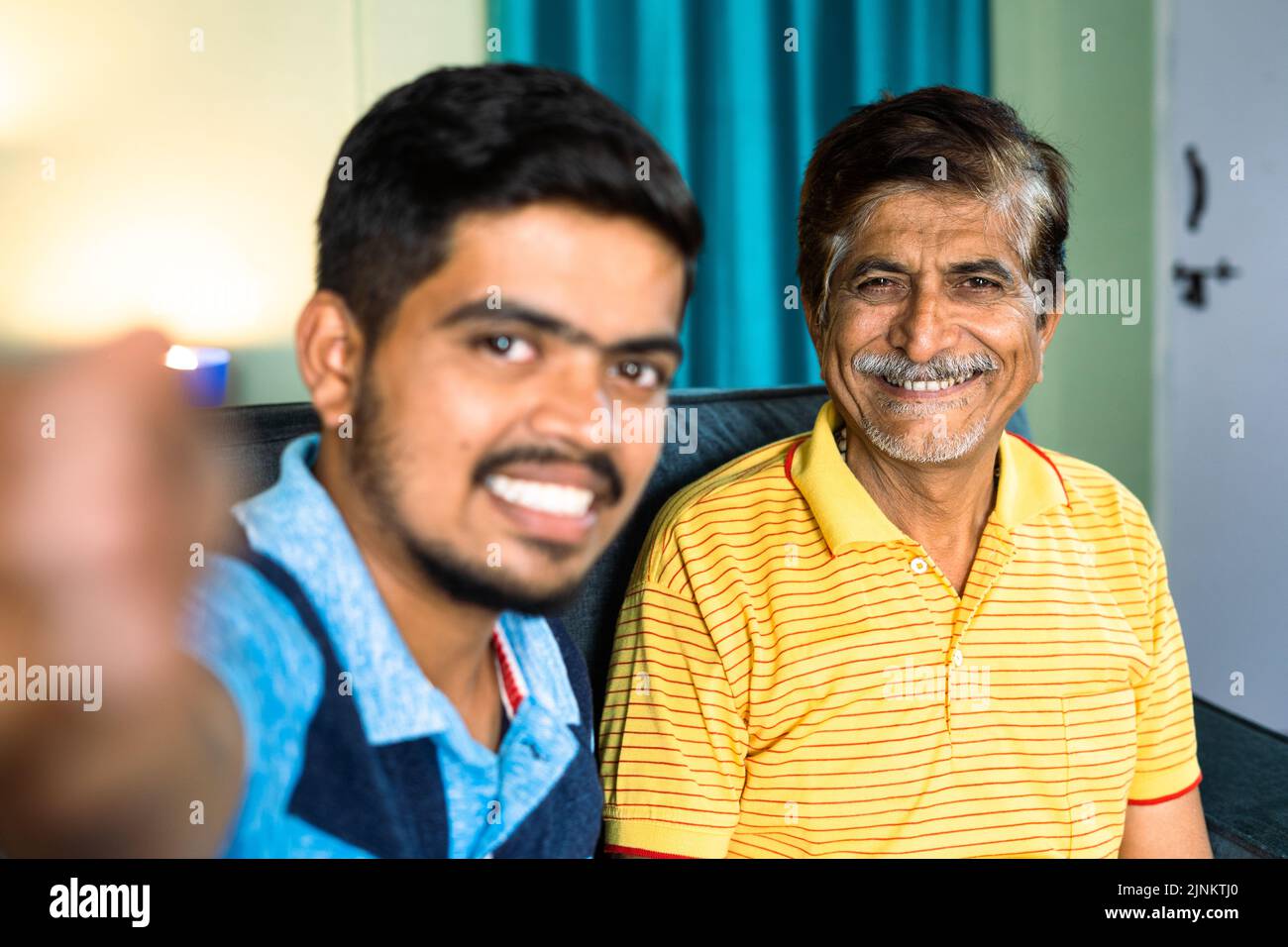 Felice figlio sorridente con padre che fa vlog o su videochiamata a casa - concetto di influencer, social video making e relazioni di legame. Foto Stock