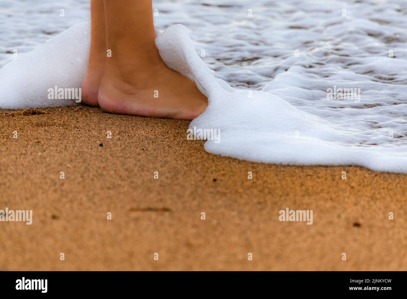 onde marine che coprono i piedi sulla spiaggia Foto Stock