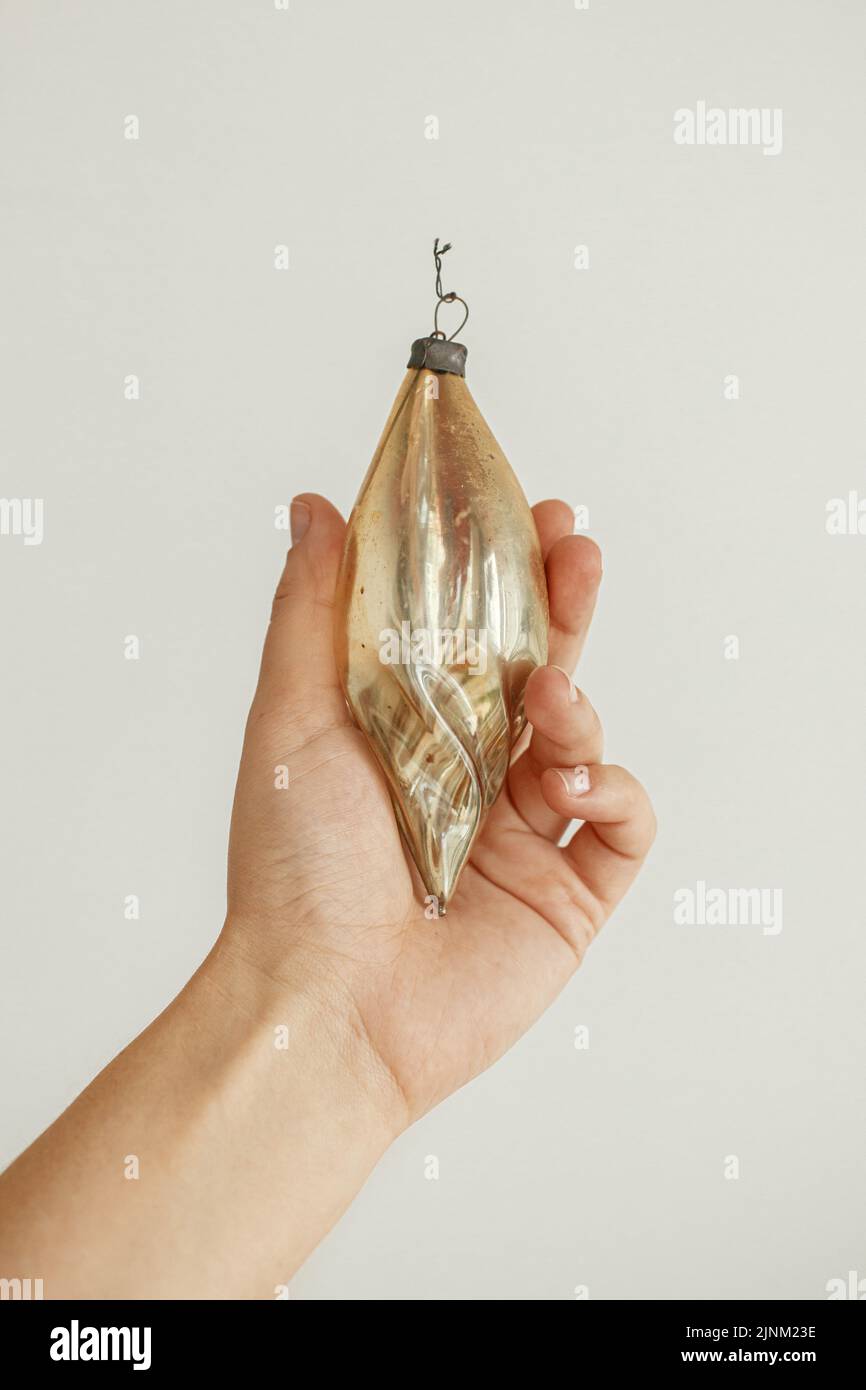 Mano che tiene ornamento di natale vintage su sfondo bianco. Buon Natale! Preparazione per le vacanze invernali, decorando l'albero di natale con stile Foto Stock