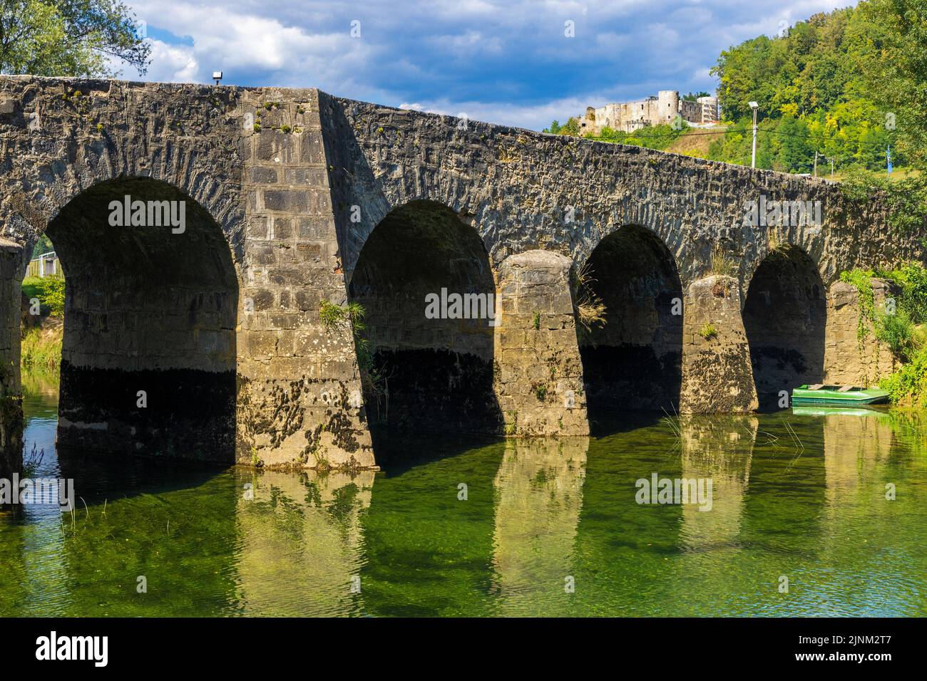 Il vecchio ponte di pietra sul fiume Dobra, con un Castello di Novigrad sullo sfondo, Croazia Foto Stock