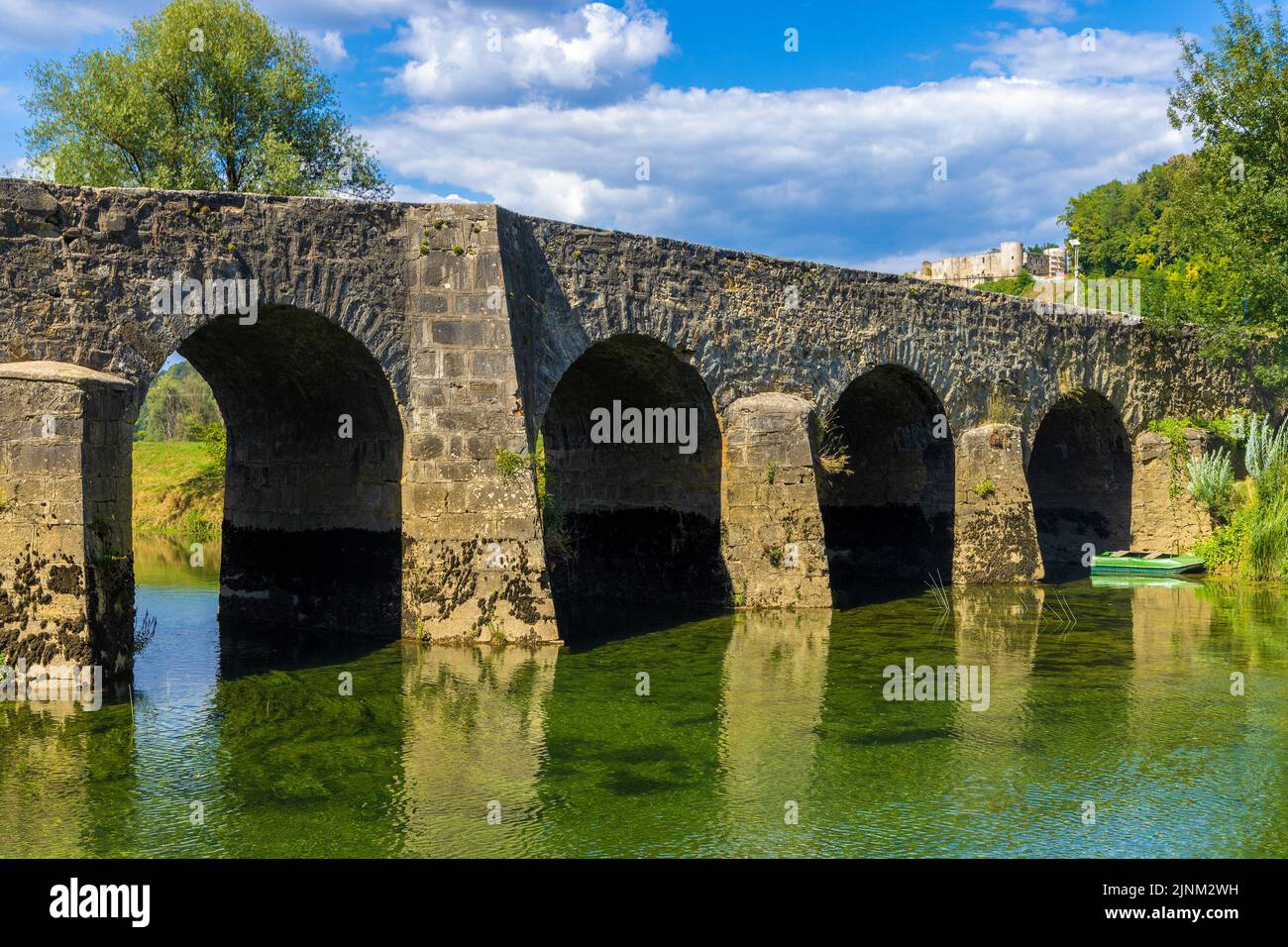 Il vecchio ponte di pietra sul fiume Dobra, con un Castello di Novigrad sullo sfondo, Croazia Foto Stock
