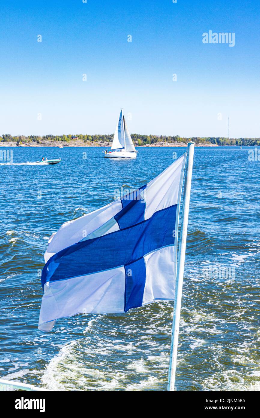 La bandiera nazionale finlandese (Siniristippu) che batte dalla poppa del traghetto Suomenlinna al largo di Helsinki, Finlandia Foto Stock