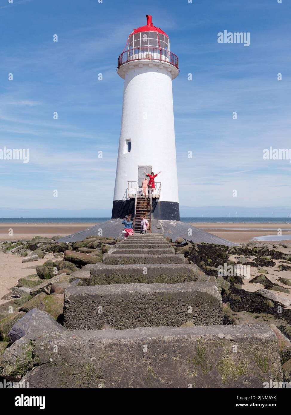 Talacre, Flintshire, Galles, 07 2022 agosto: Punto di Ayr Lighthouse aka Talacre Lighthouse, un edificio classificato di II grado situato sulla spiaggia. Signora in rosso Foto Stock