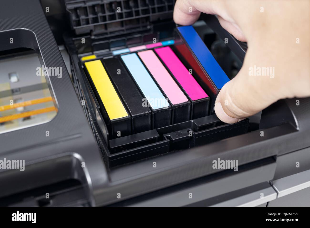 Mano umana che sostituisce una cartuccia di inchiostro blu di una stampante a getto d'inchiostro multicolore Foto Stock