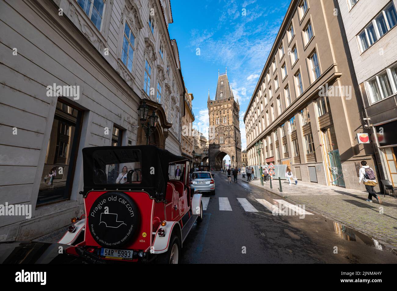 Strada con auto vecchia nel centro storico di Praga con la famosa Torre delle polveri (in ceco: Prašná brána) sullo sfondo. Foto Stock