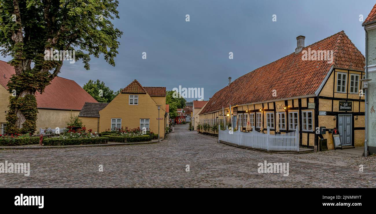 Panoramica di una piazza di ciottoli e il vecchio albergo con cornice in legno Postgaarden nella luce notturna crepuscolo, Mariager, Danimarca, 7 agosto 2022 Foto Stock