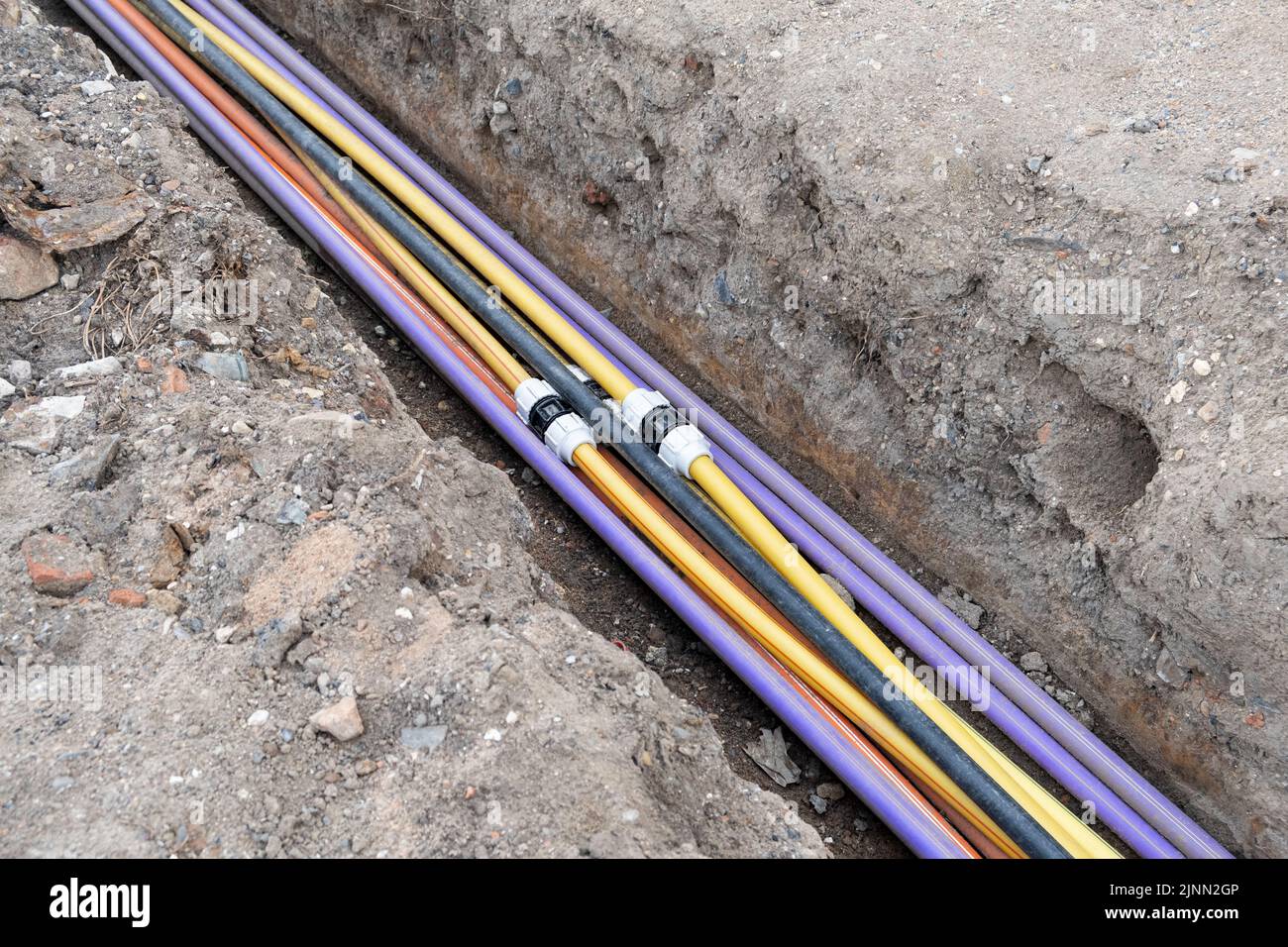 installazione di infrastrutture per cavi elettrici sotterranei. Cantiere con molti cavi di comunicazione protetti in tubi. elettrico e alta-spe Foto Stock