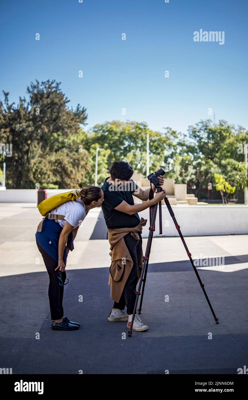 due persone, uomo e donna che scattano foto con cavalletto, pavimento in cemento, giorno di sole Foto Stock