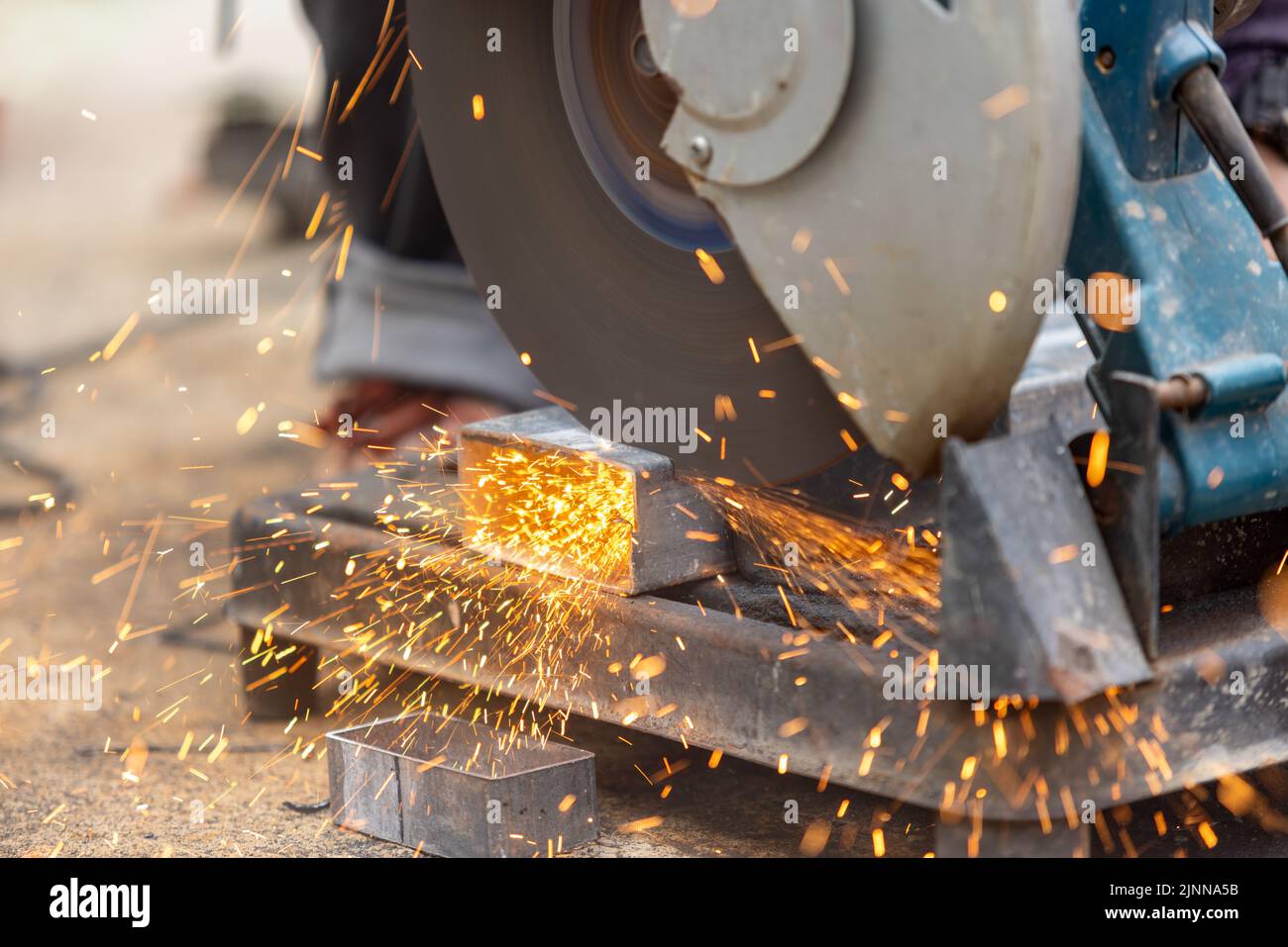 Lavoratore che taglia tubi rettangolari in acciaio in cantiere. Foto Stock