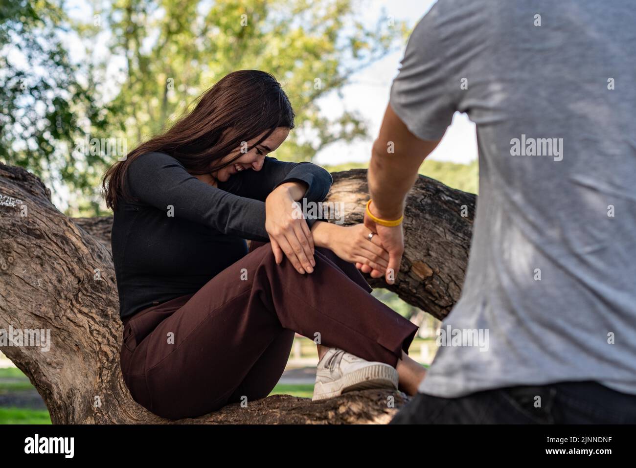 Il giovane uomo prende la mano di una bella ragazza che le chiede di andare con lui. Lei ride e sembra essere felice Foto Stock