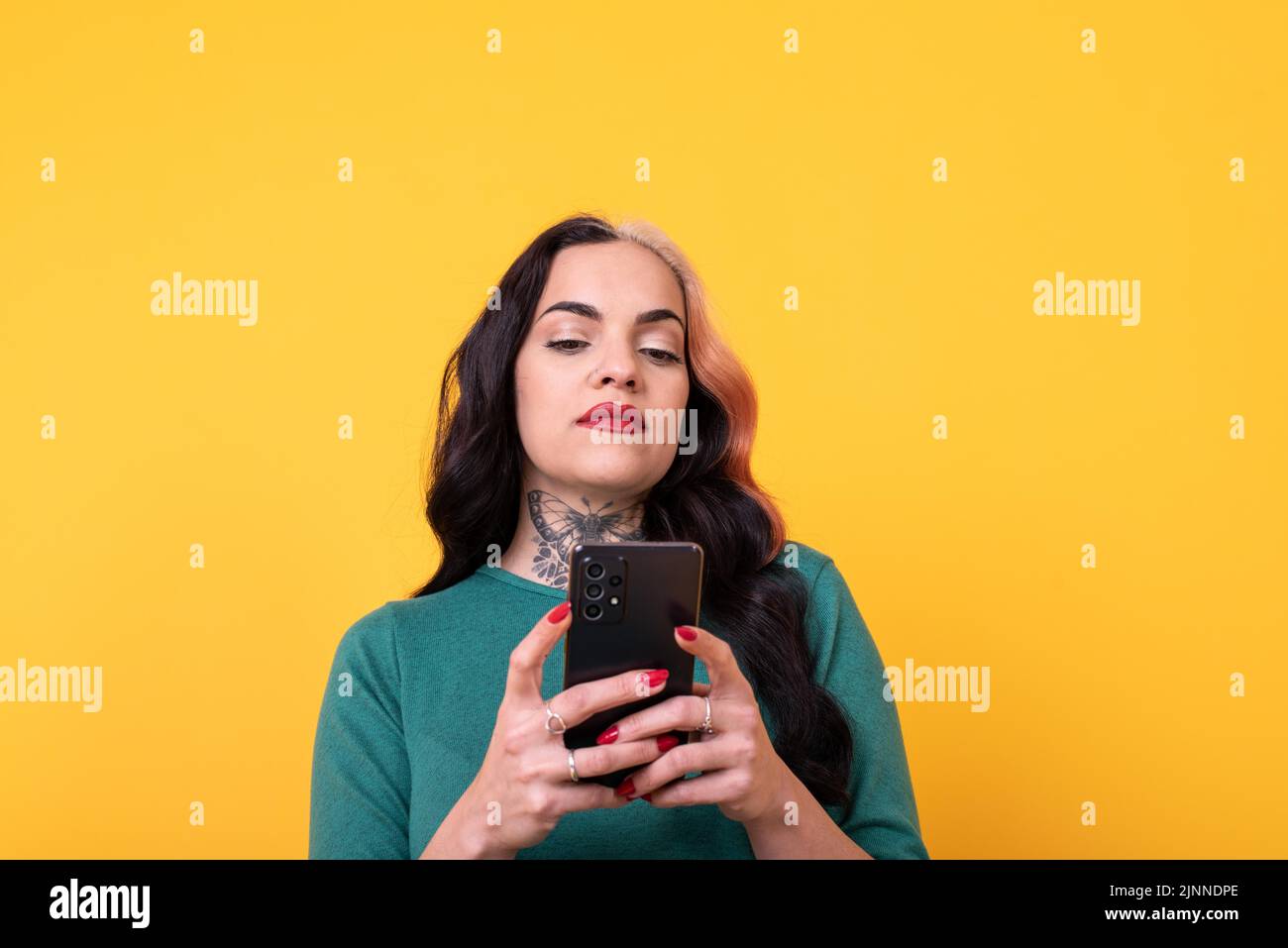 Ritratto di una donna attraente utilizzando smartphone su sfondo giallo. Spazio di copia Foto Stock
