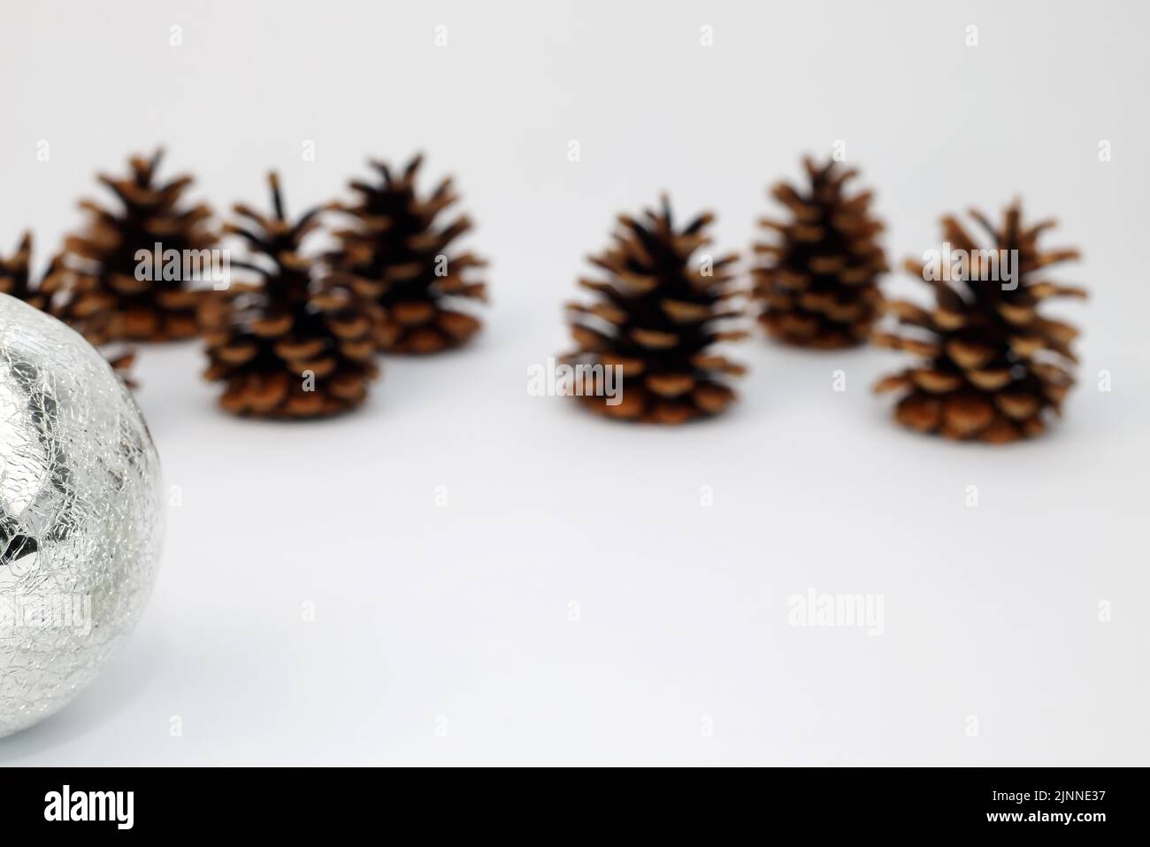 Sfera d'argento dell'albero di Natale e cono di abete o cono del pino tagliato su fondo bianco con gradiente di affilatura Foto Stock