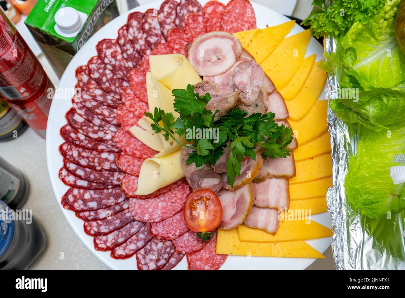 Un piatto di antipasti freddi con varie salsicce, carne e formaggio. Verdi e pomodori. Foto Stock