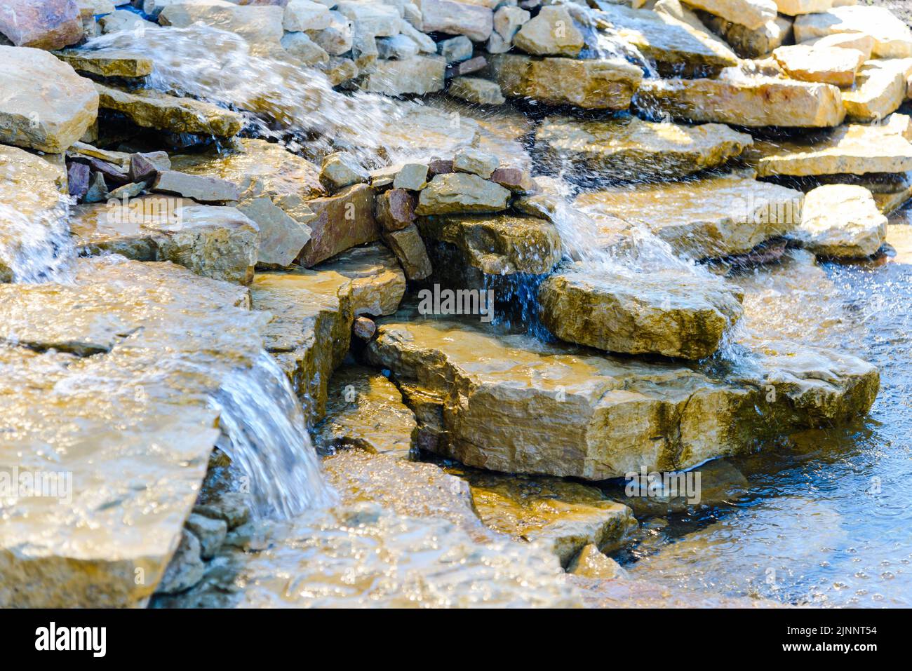 Bel ruscello fresco e rinfrescante lungo le pietre e le rocce in un giorno d'estate luminoso.Closeup. Foto Stock