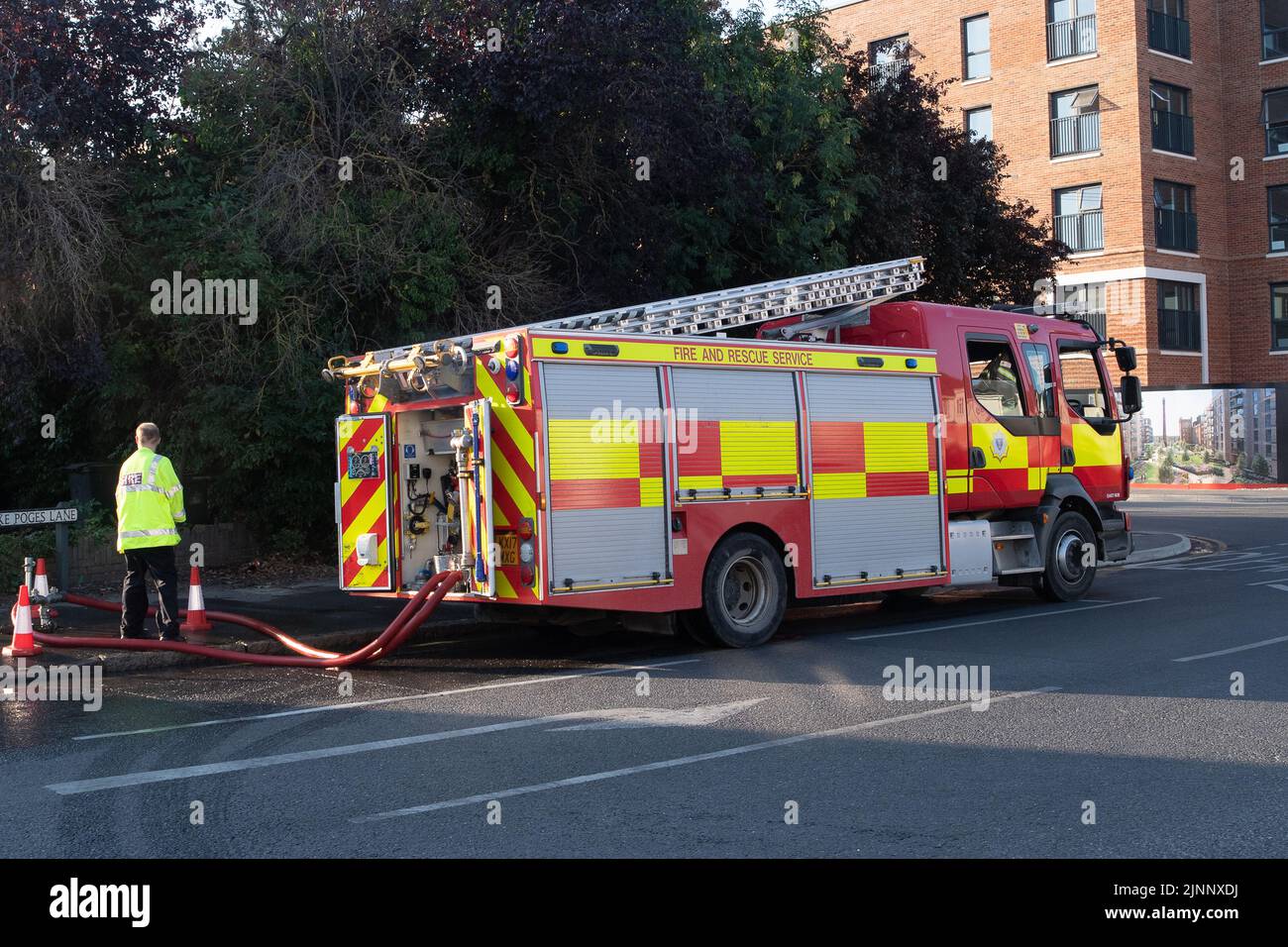 Slough, Berkshire, Regno Unito. 13th agosto, 2022. Un motore antincendio aspira l'acqua da un idrante. Il Royal Berkshire Fire and Rescue Service stavate mettendo fuori un fuoco presso lo stabilimento di riciclaggio Simpson a Simpsons Way, Slough questa mattina dietro il Tempio di Ramgarhia Sikh. Ai residenti è stato consigliato di rimanere all'interno e tenere le finestre chiuse. Un camion Zetros che contiene 8.000 litri d'acqua è stato anche sulla scena per smorzare il fuoco. Credit: Maureen McLean/Alamy Live News Foto Stock