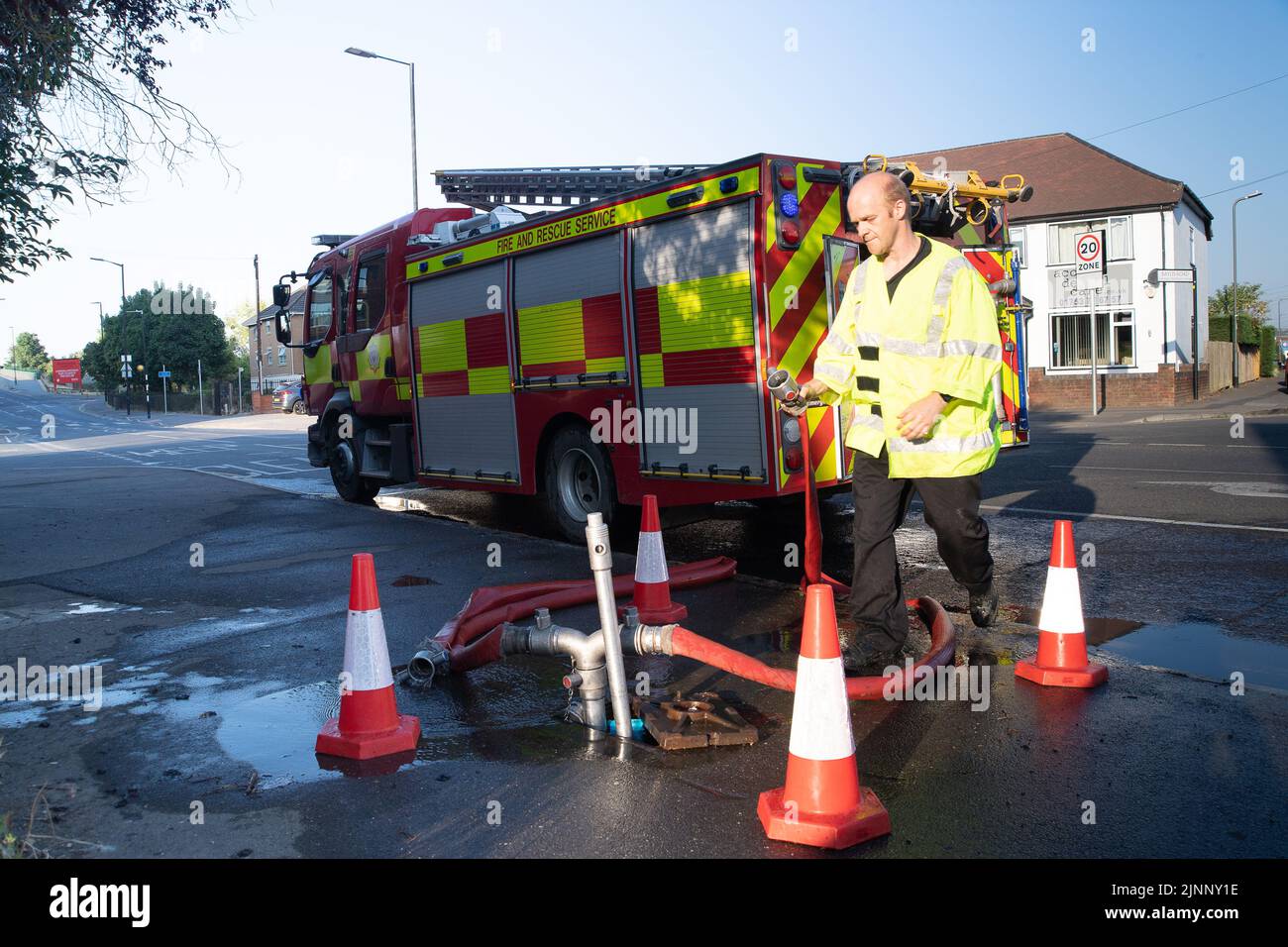 Slough, Berkshire, Regno Unito. 13th agosto, 2022. Un motore antincendio aspira l'acqua da un idrante. Il Royal Berkshire Fire and Rescue Service stavate mettendo fuori un fuoco presso lo stabilimento di riciclaggio Simpson a Simpsons Way, Slough questa mattina dietro il Tempio di Ramgarhia Sikh. Ai residenti è stato consigliato di rimanere all'interno e tenere le finestre chiuse. Un camion Zetros che contiene 8.000 litri d'acqua è stato anche sulla scena per smorzare il fuoco. Credit: Maureen McLean/Alamy Live News Foto Stock