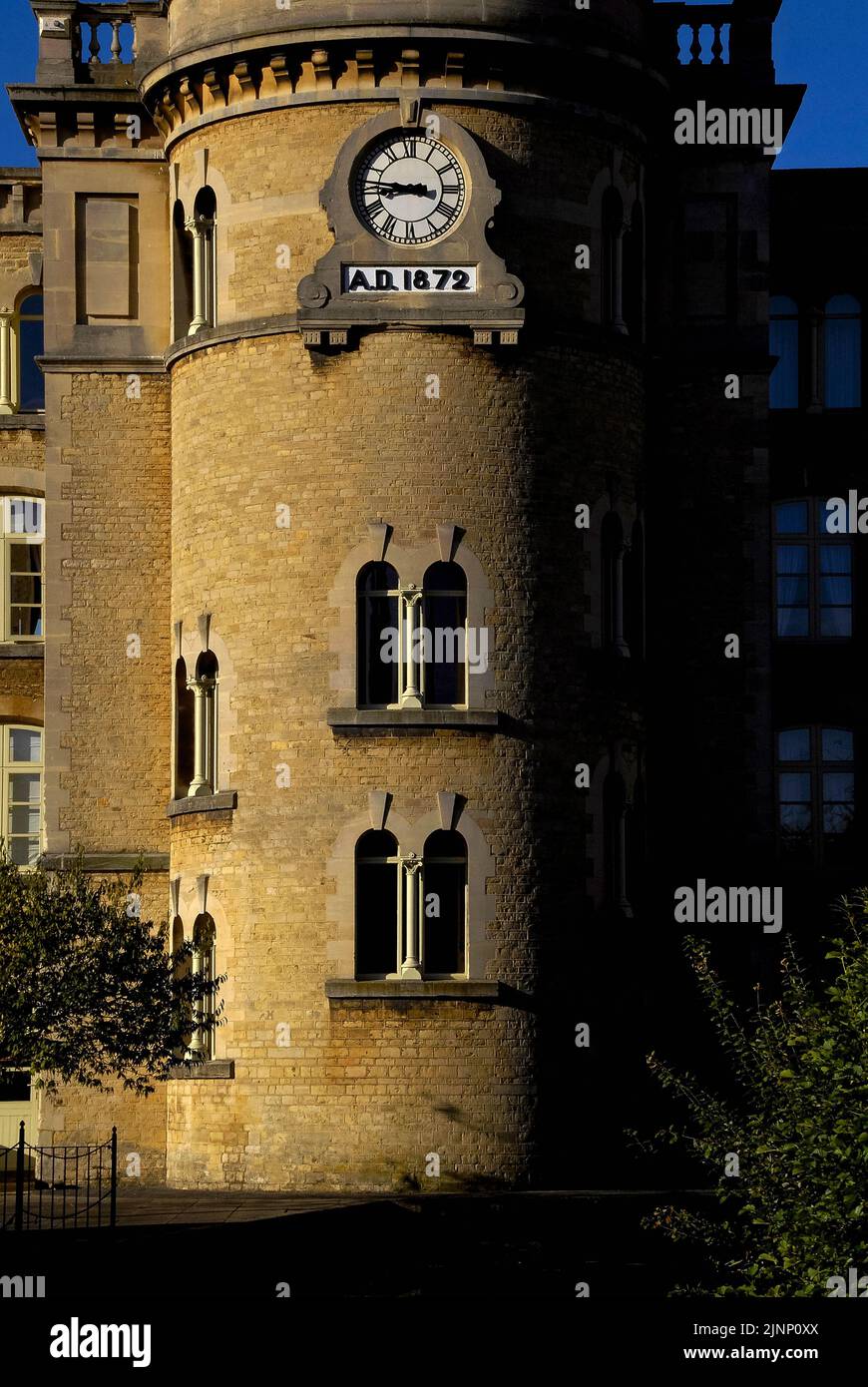 Tempo presente e tempo passato... Sulla torre che sorregge l'imponente camino dell'ex Bliss Tweed Mill di Chipping Norton, Oxfordshire, Inghilterra, Regno Unito, un orologio a quadrante sormonta la data «A.D. 1872’, l’anno in cui il mulino è stato costruito e ha iniziato la produzione di tessuti di alta qualità in tweed filati e tessuti di lana Cotswold e Shetland. Nella prima guerra mondiale del 1914-18, ha realizzato un panno kaki per le uniformi dei soldati britannici. Foto Stock