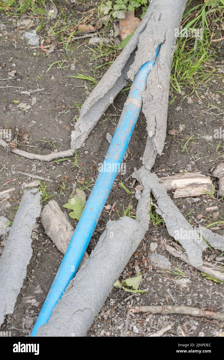 Involucro protettivo rotto del tubo dell'acqua di alkathene blu usato per trasportare l'acqua potabile - trasportato vicino ad una pista dell'azienda agricola. Foto Stock