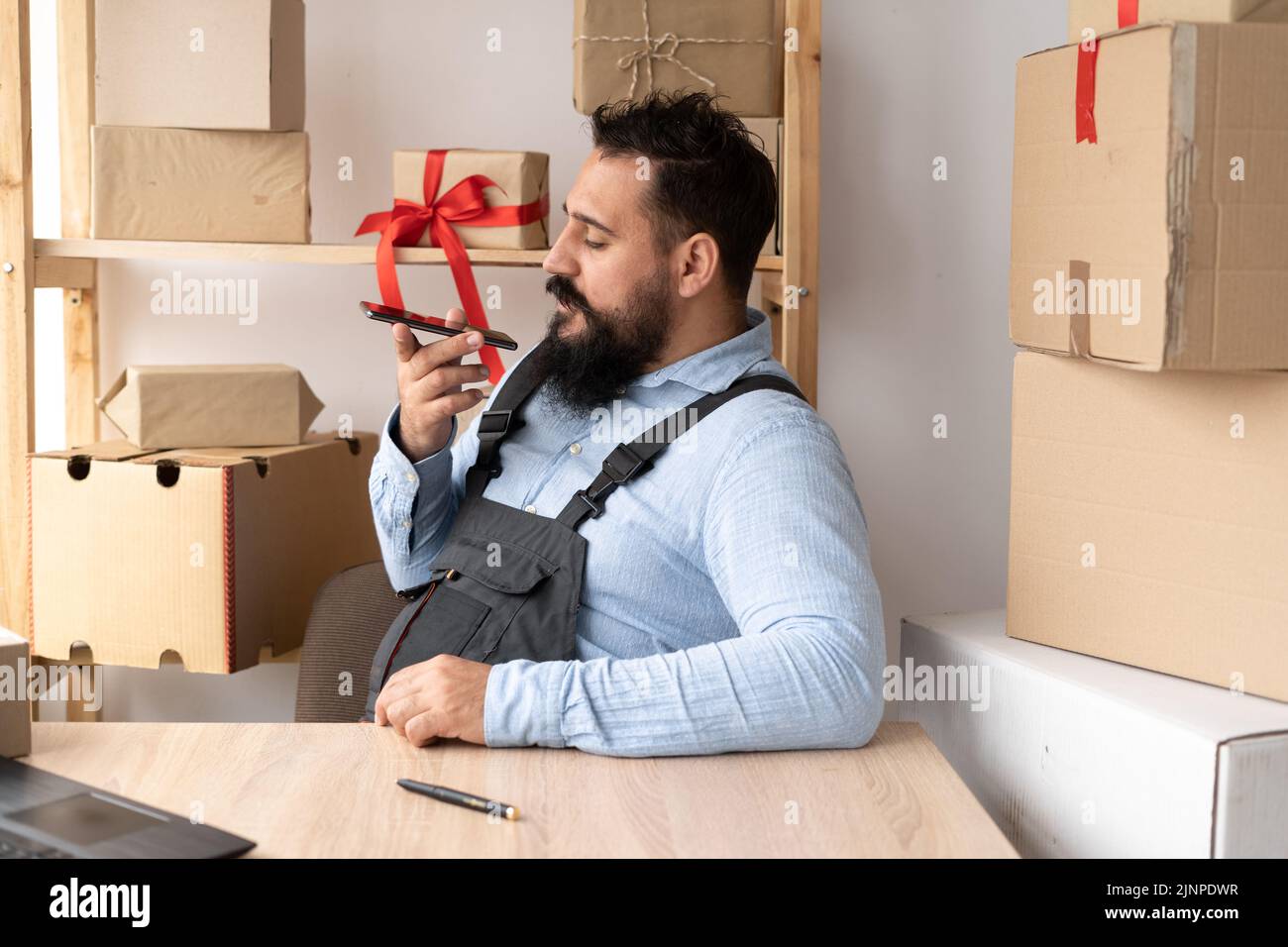 Uomo d'affari millenario che utilizza lo smartphone in negozio, registra i messaggi utilizzando l'assistente vocale sul telefono cellulare. E-commerce maschio imprenditore Foto Stock