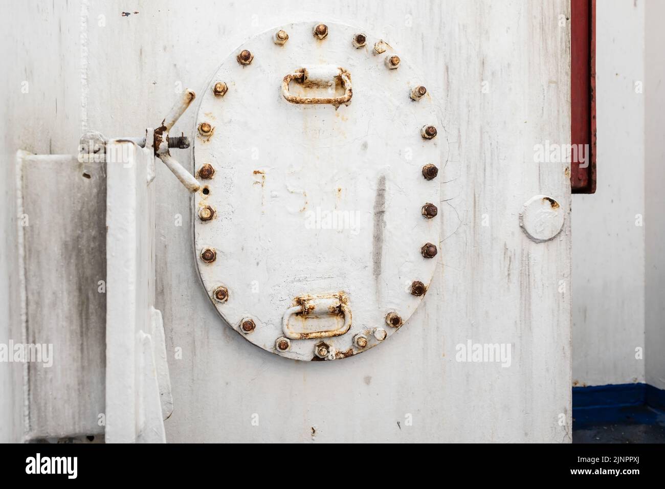 Dettagli di una porta di ferro bianca sulla nave, con rivetti e ruggine, e una serratura a torsione. Foto Stock