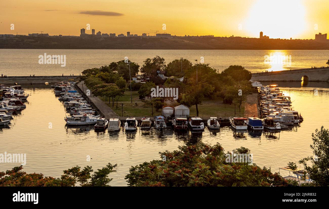 Kucukcekmece, Istanbul, Turchia - Giugno 29 2022: Ponte di pietra e barche da pesca sul lago nel quartiere Kucukcekmece di Istanbul. Al tramonto Foto Stock