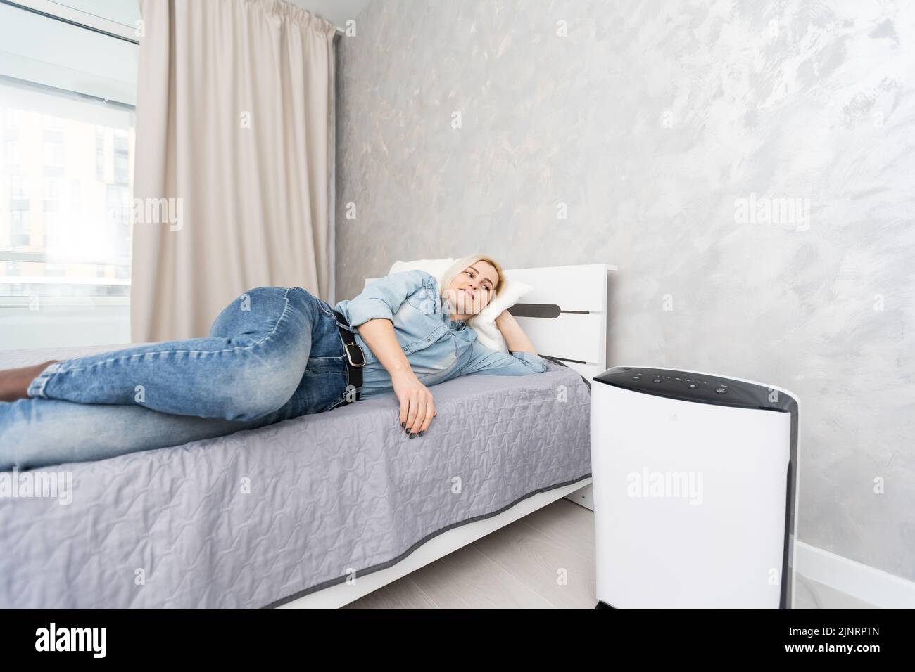 Donna che si rilassa a casa con l'umidificatore d'aria funzionante in primo  piano. Concetto di umidificazione dell'aria domestica Foto stock - Alamy