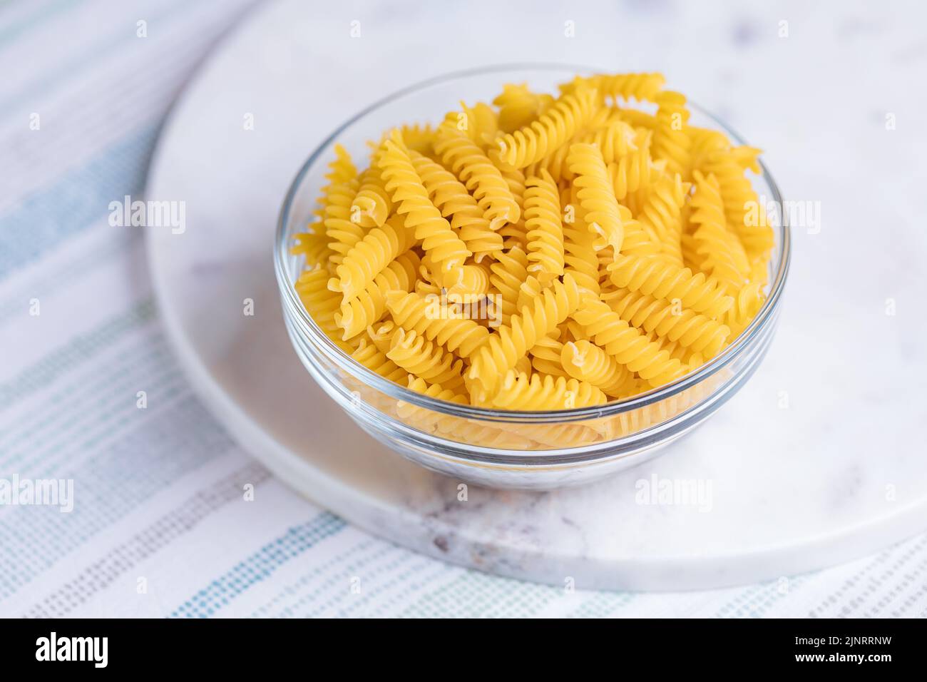 Fusili crudo con altri ingredienti su sfondo luminoso. Piatto italiano tradizionale. Foto Stock