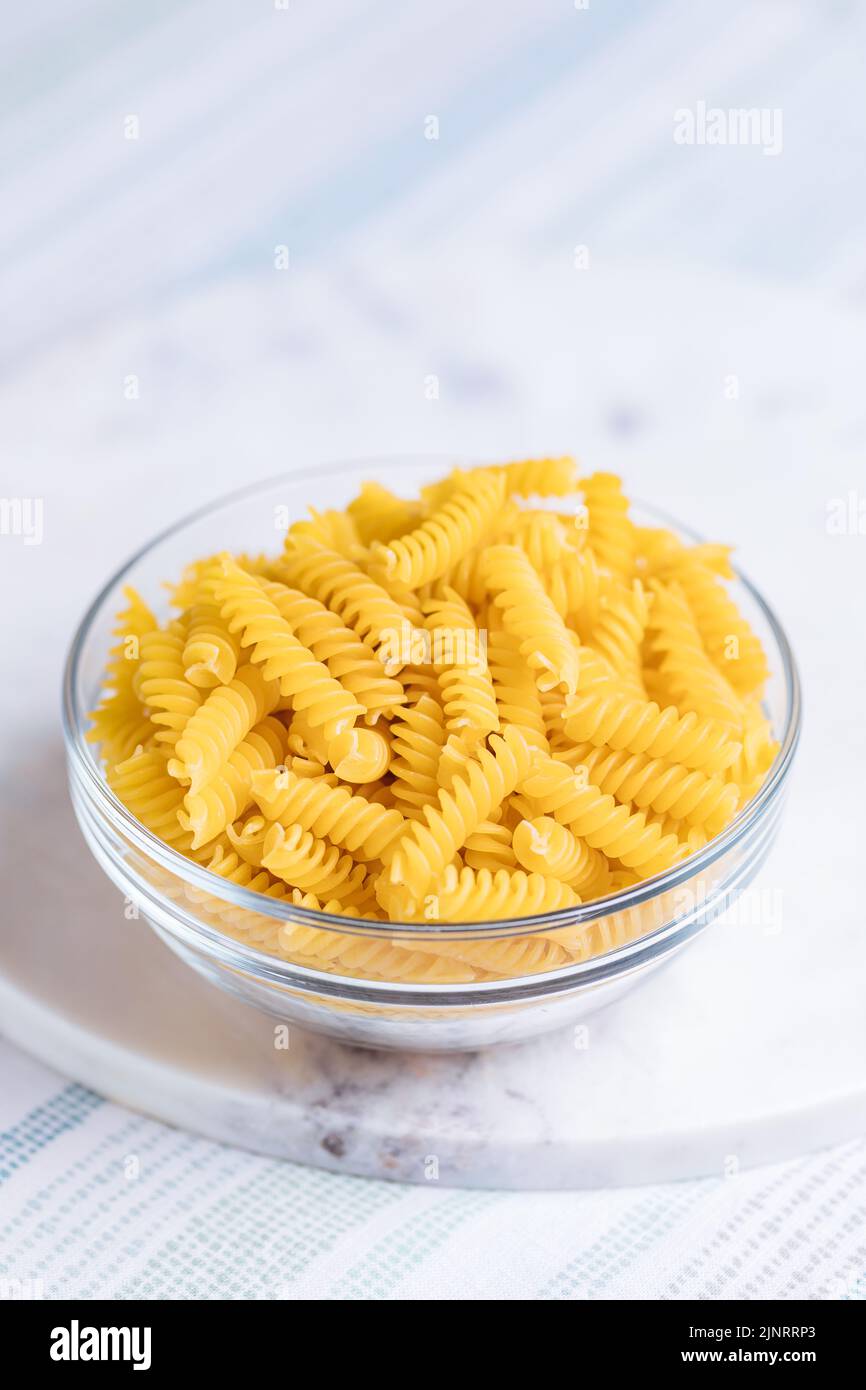 Fusili crudo con altri ingredienti su sfondo luminoso. Piatto italiano tradizionale. Foto Stock