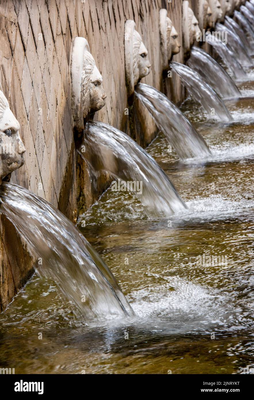 fila di fontane con teste di maschera leone che rovinano l'acqua in un bagno di città termale o in un trogolo per pompare attraverso la fontana come caratteristica del giardino Foto Stock