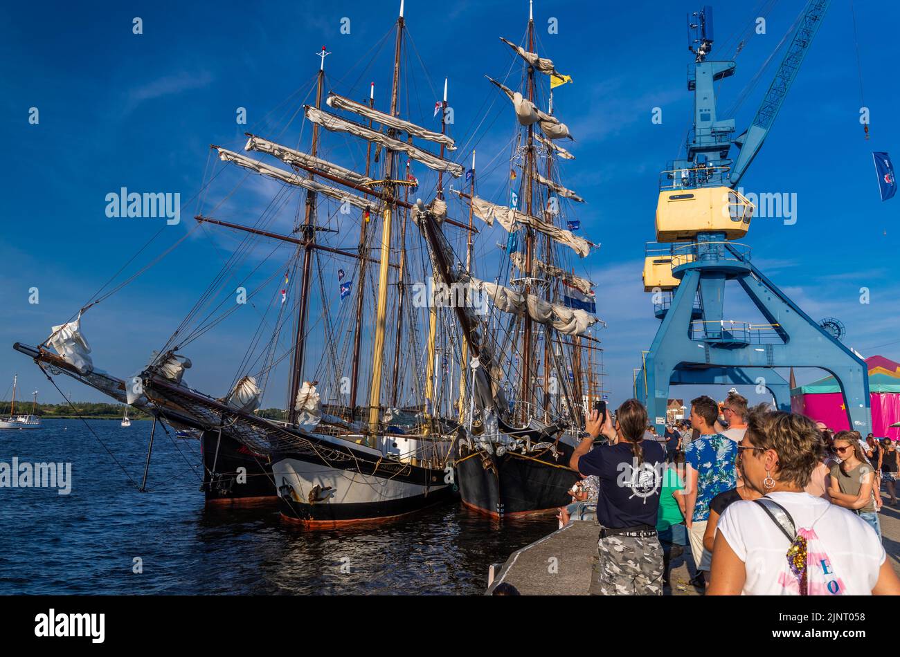 Rostock, Germania. 13th ago, 2022. Barche a vela storiche e navi tradizionali sono ormeggiate nel porto della città in serata come ospiti della Hanse Sail. Dopo la cancellazione della corona nel 2020 e la più piccola edizione anniversario dello scorso anno, la Hanse Sail è ancora una volta il più grande festival di folclore marittimo di Meclemburgo-Pomerania occidentale quest'anno con 111 navi tradizionali e centinaia di migliaia di visitatori attesi. Credit: Jens Büttner/dpa/Alamy Live News Foto Stock