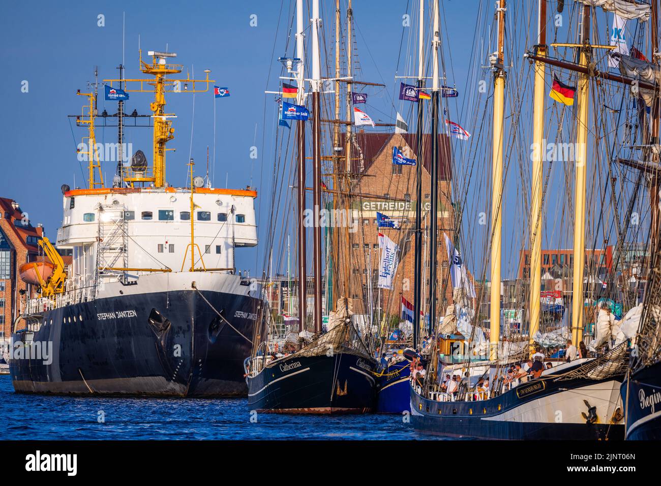 Rostock, Germania. 13th ago, 2022. Barche a vela storiche e navi tradizionali sono ormeggiate nel porto della città in serata come ospiti della Hanse Sail. Dopo la cancellazione della corona nel 2020 e la più piccola edizione anniversario dello scorso anno, la Hanse Sail è ancora una volta il più grande festival di folclore marittimo di Meclemburgo-Pomerania occidentale quest'anno con 111 navi tradizionali e centinaia di migliaia di visitatori attesi. Credit: Jens Büttner/dpa/Alamy Live News Foto Stock