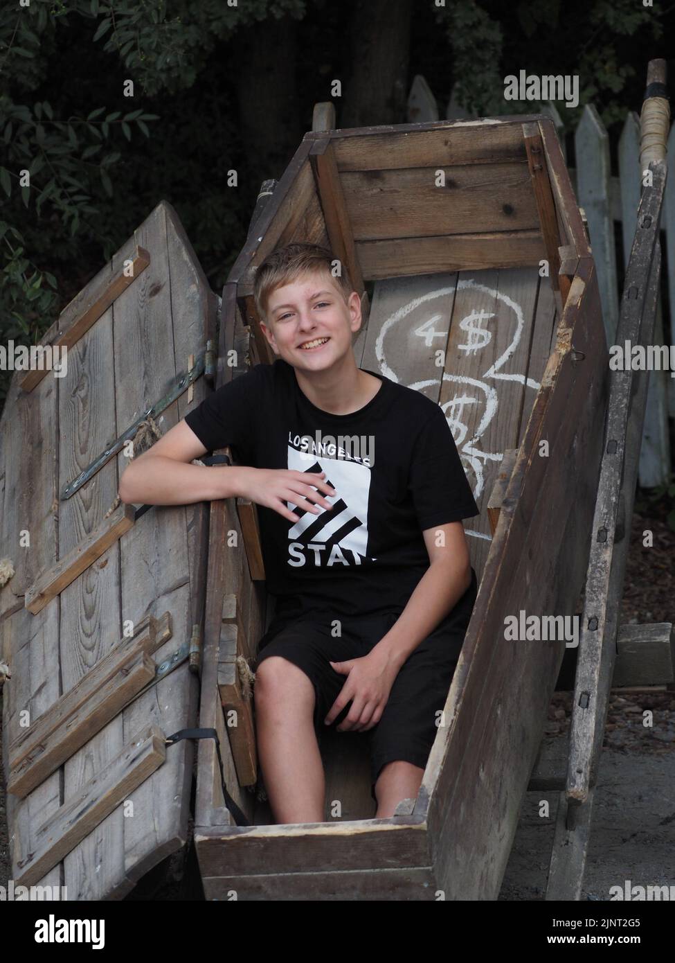 Sorridente adolescente si pone per una foto in una bara di legno a Pullman City Foto Stock