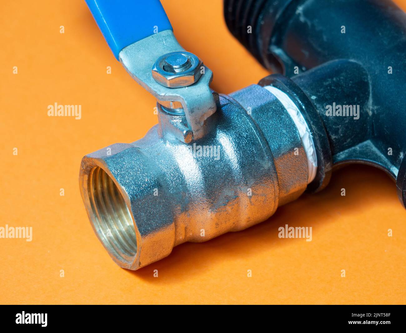 valvola dell'acqua su sfondo arancione. Concetto di irrigazione Foto Stock