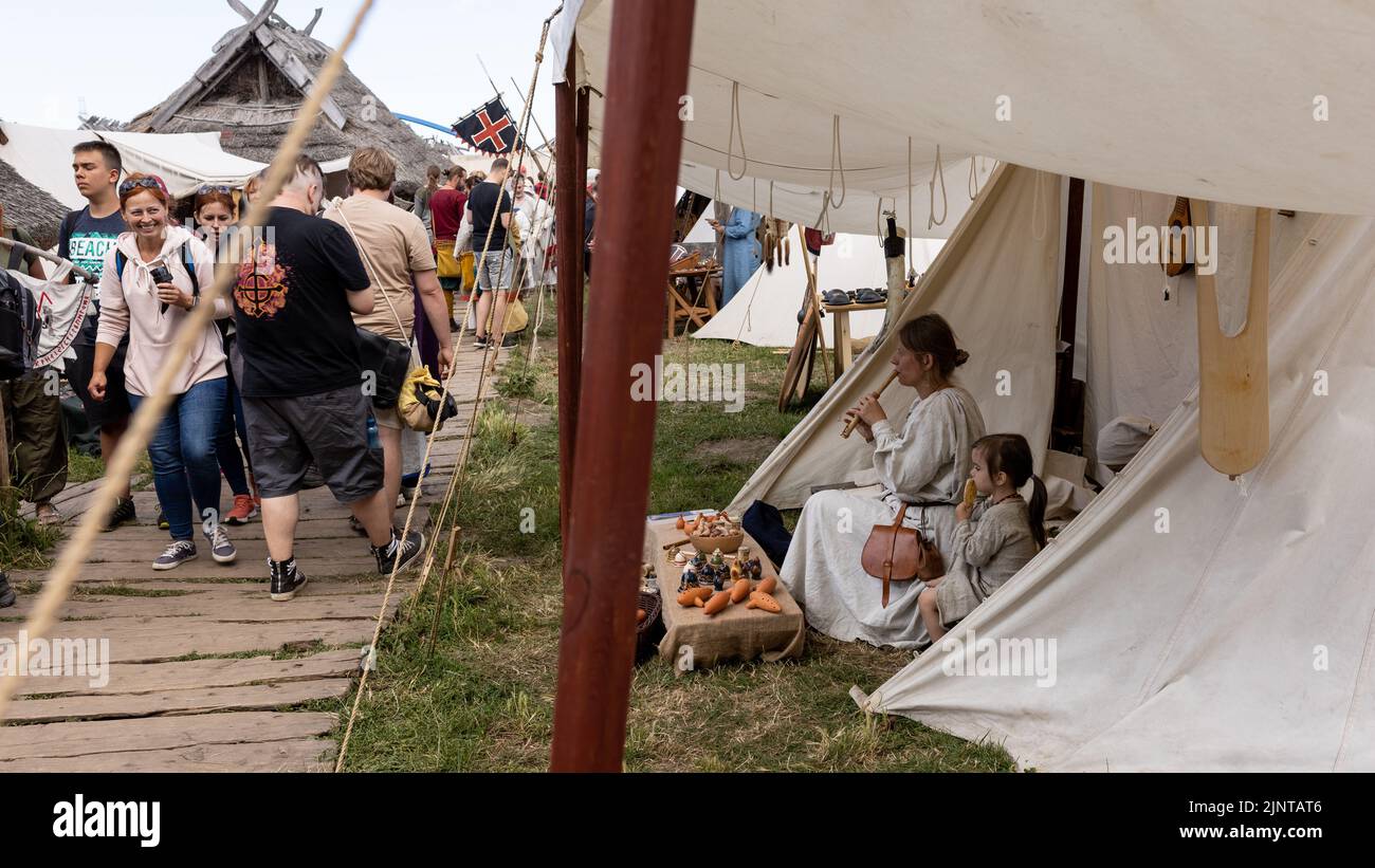 WOLIN, POLONIA - 6 AGOSTO 2022: XXVII Festival di Slavi e Vichinghi, donna vestita medievale che gioca flauto di legno vicino alla tenda Foto Stock