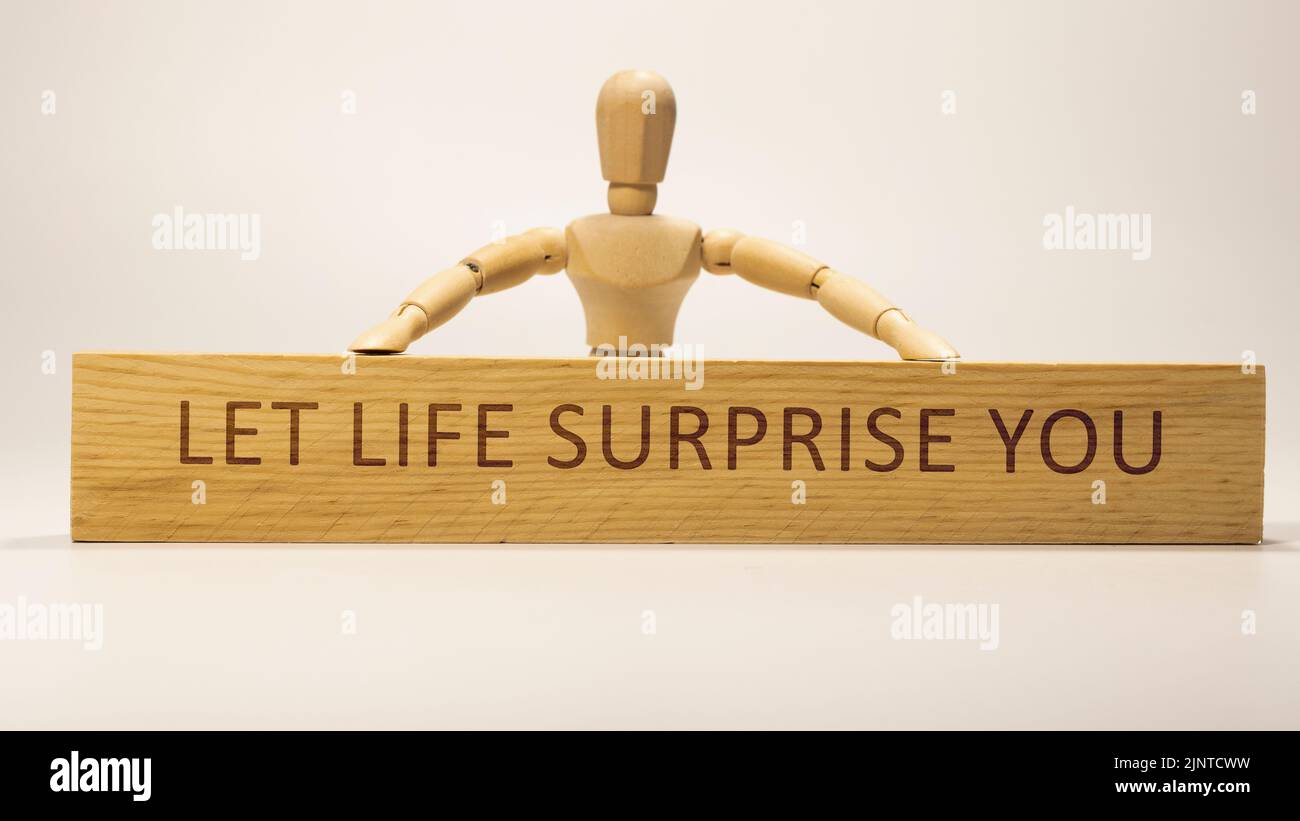 Lasciate che la vita vi sorprenda scritto su superficie di legno. Motivazione e sviluppo personale Foto Stock