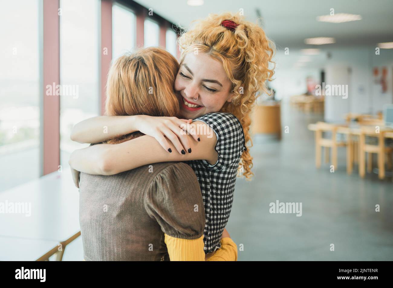 Gli studenti adolescenti felici abbracciando in biblioteca Foto Stock