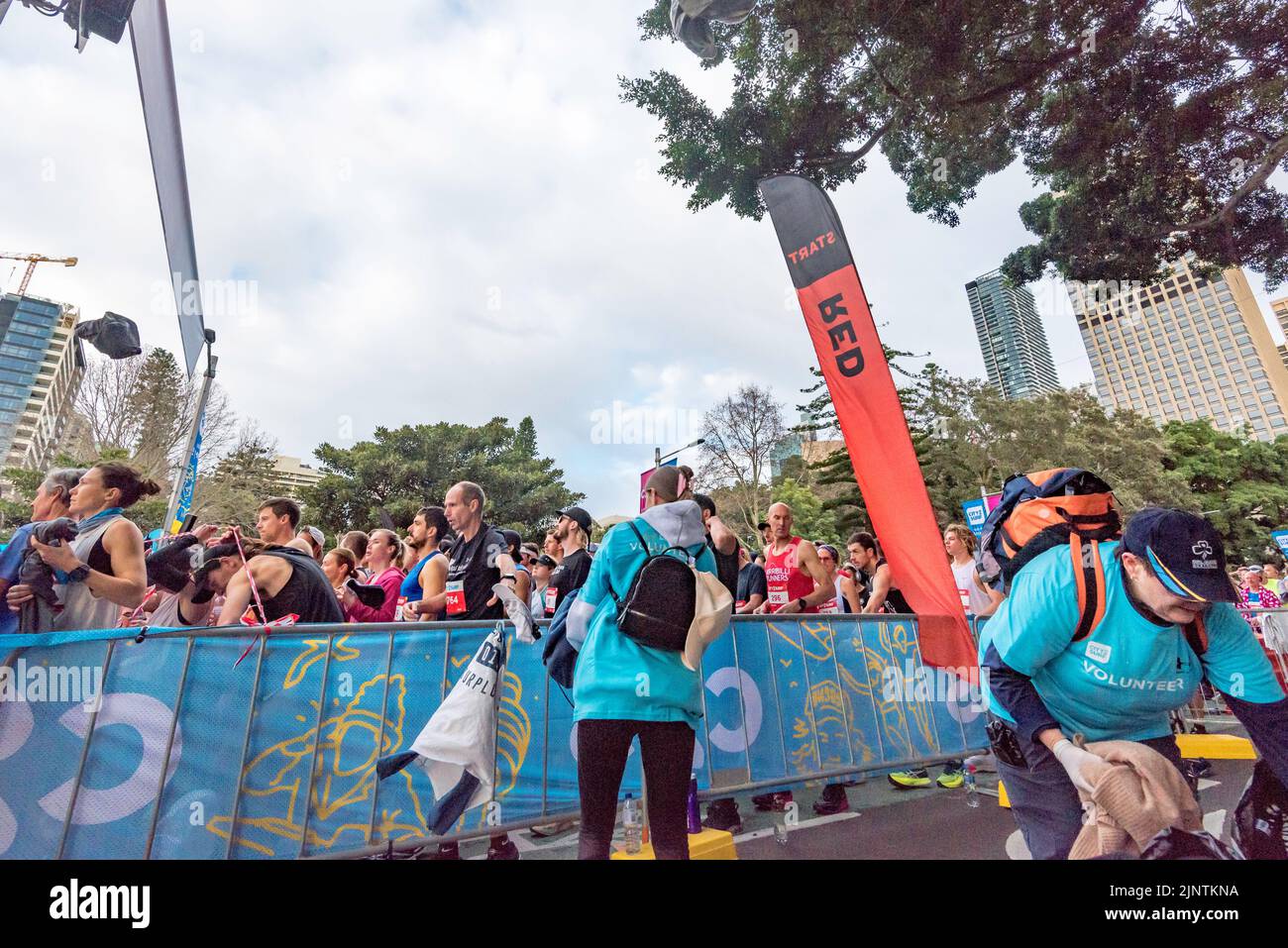 Sydney, Australia, 14 agosto 2022: Oltre 60.000 persone partecipano alla gara del 50th City2Surf a Sydney, la prima dal 2019 dopo le cancellazioni nel 2020 e nel 2021 a causa delle restrizioni del Covid-19. Sullo sfondo di ogni gara ci sono volontari che aiutano l'evento a correre senza intoppi. Nella foto, i membri di Girl Guides Australia raccolgono gli indumenti esterni di pre-partenza del runner scartati mentre vola sopra la barricata verso di loro. L'abbigliamento donato viene successivamente trasferito alle associazioni di beneficenza. Credit: Stephen Dwyer / Alamy Live News Foto Stock