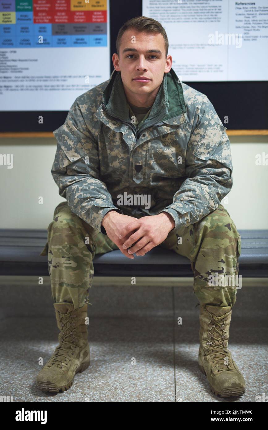 Un giovane soldato seduto su una panchina nella sala di un'accademia militare. Foto Stock