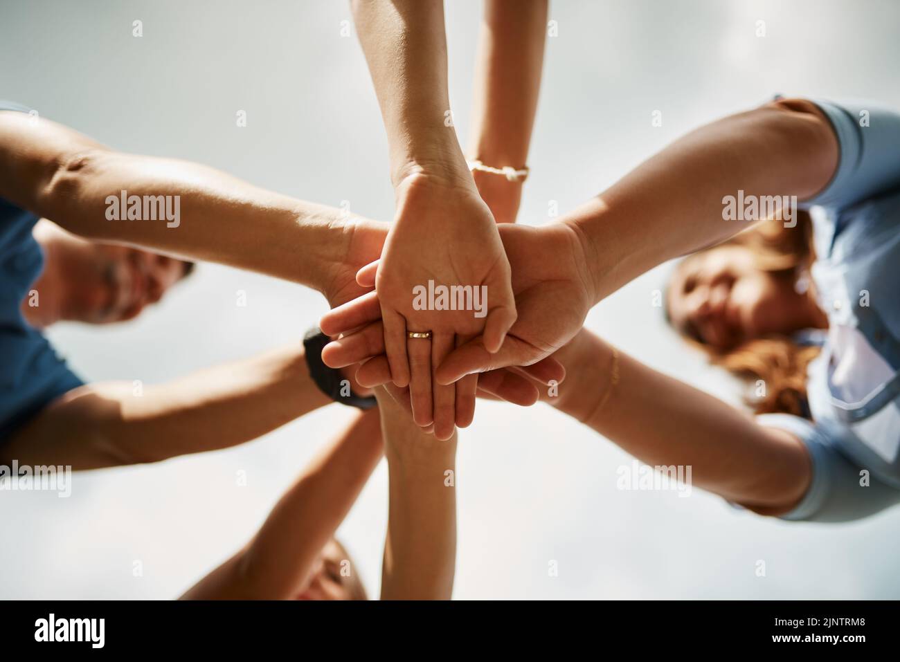 Questa famiglia è tutto per uno. Inquadratura ad angolo basso di una famiglia di quattro persone in piedi con le mani in una tuddle. Foto Stock