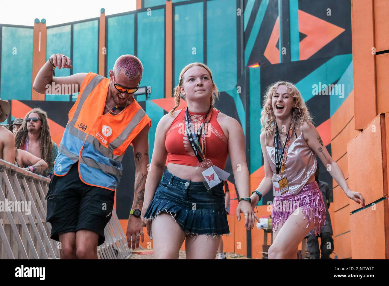 I volontari dell'Oxfam Festival ballano e guardano le band sul Grand Central Stage al Fair Festival. Boomtown Festival - Capitolo 1: Il raduno - si svolge presso la tenuta di Matterley, vicino a Winchester, Hampshire, e si svolgerà da mercoledì 10th a domenica 14th agosto 2022. Boomtown segue una storia che si evolve ogni anno, ed è stato resettato per il mondo post-pandemico dove lo Stato di emergenza è diventato uno Stato di emergenza che è sorto dalle ceneri del vecchio. È un mondo nuovo, accompagnato da una nuova storia che aspetta di essere raccontata e che si concentra sulla riflessione, l'accettazione e la riconnessione Foto Stock